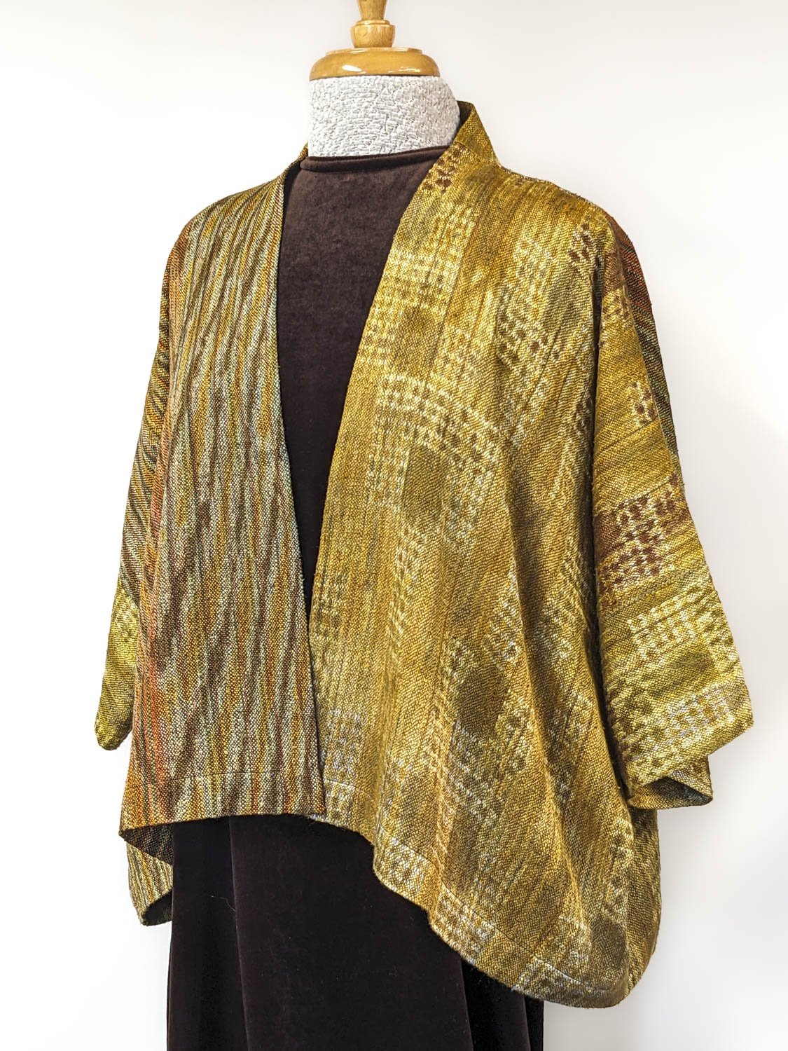 Gold and multicolored handwoven kimono-style silk jacket on mannequin, over black top and pants.