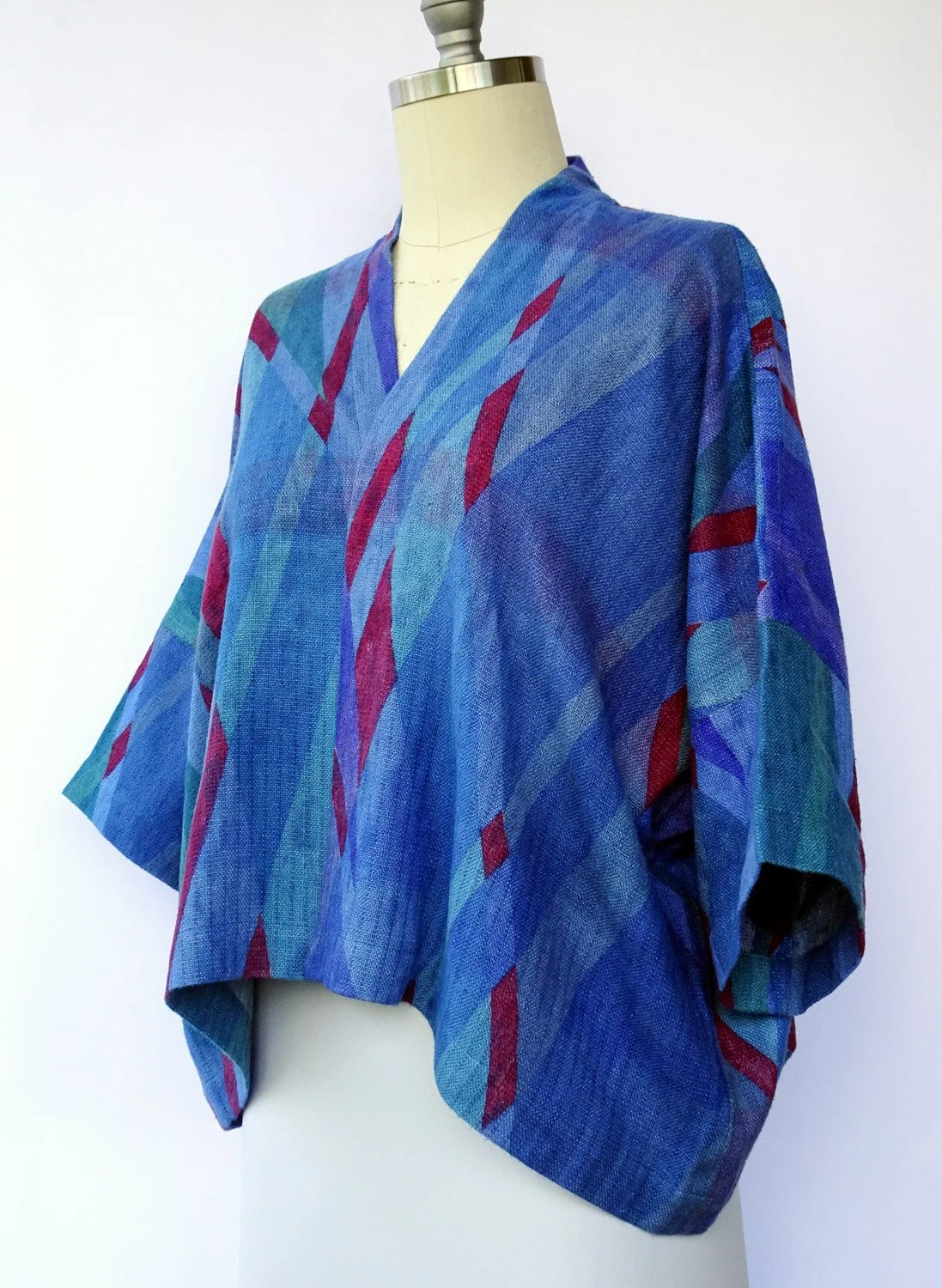 A mannequin wearing a loose, multicolored kimono with shades of blue, purple, and red abstract patterns, against a white background.