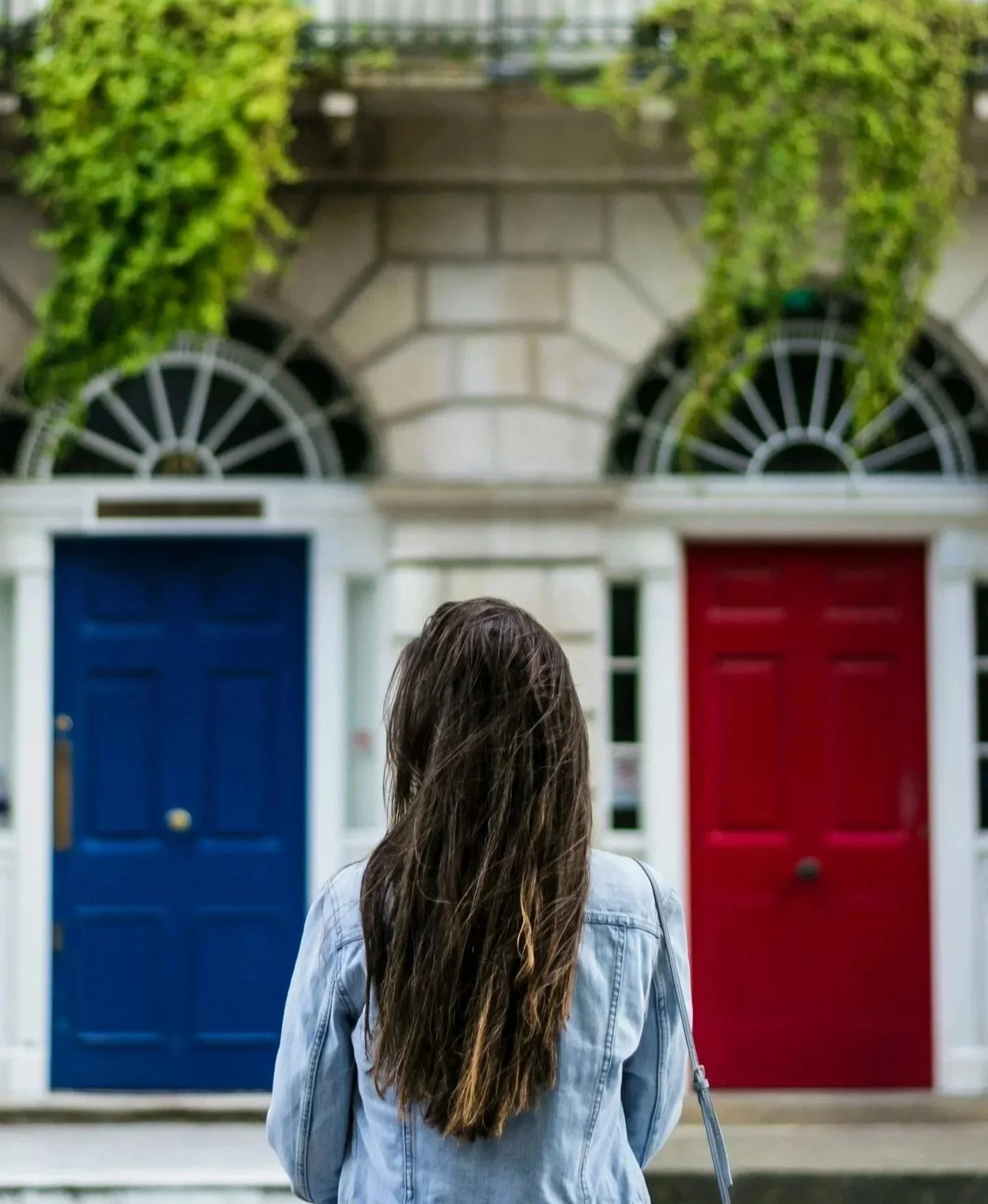 Person standing in front of two colorful doors on a city street.