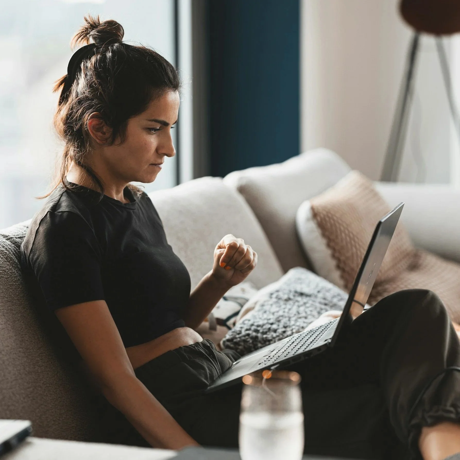 Woman sitting on a couch using a laptop with a focused expression