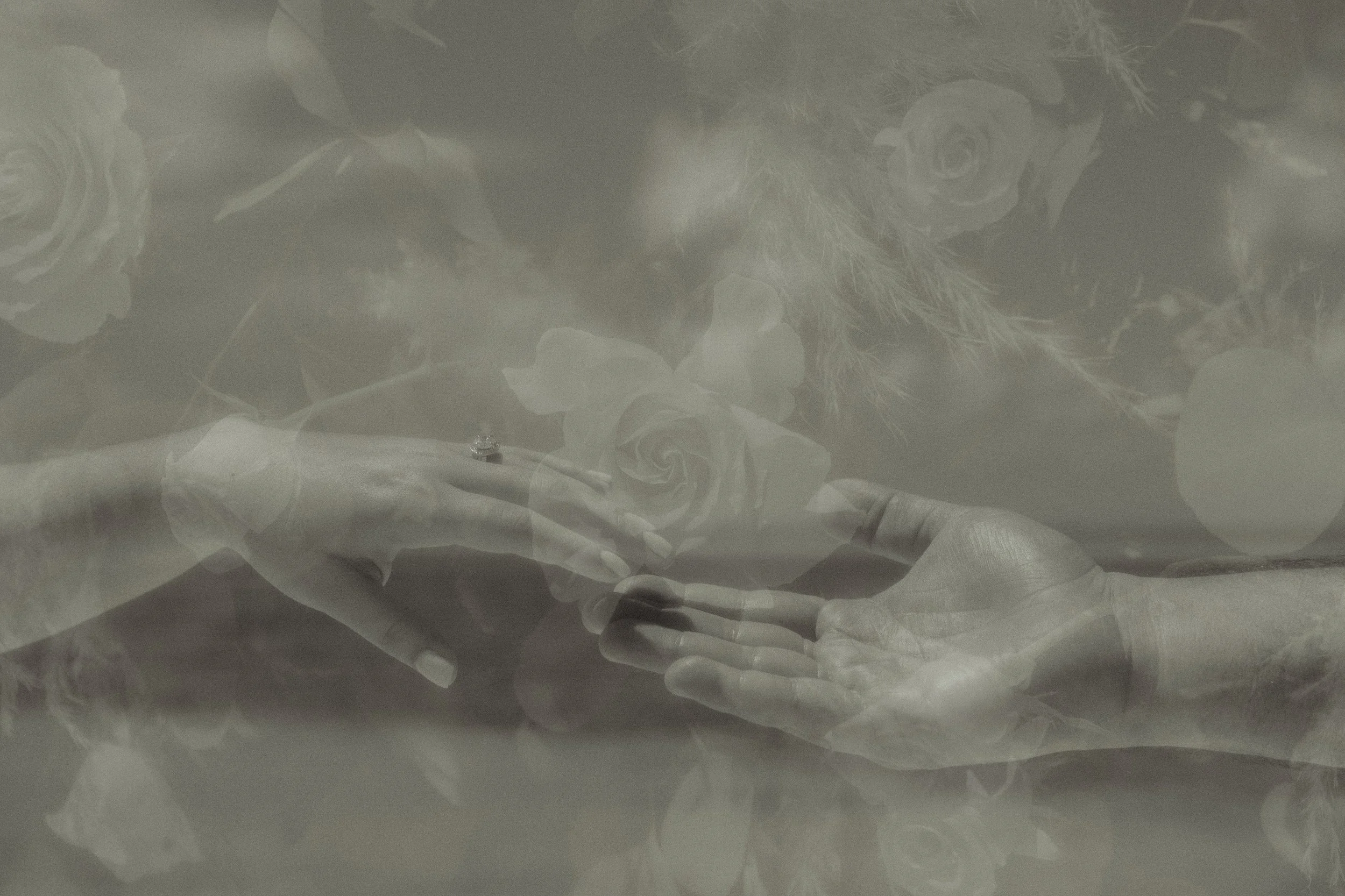 Photo in black in white of a double exposure of a couple's hands touching with flowers overlaying captured by Emmedelmar in Cozumel.
