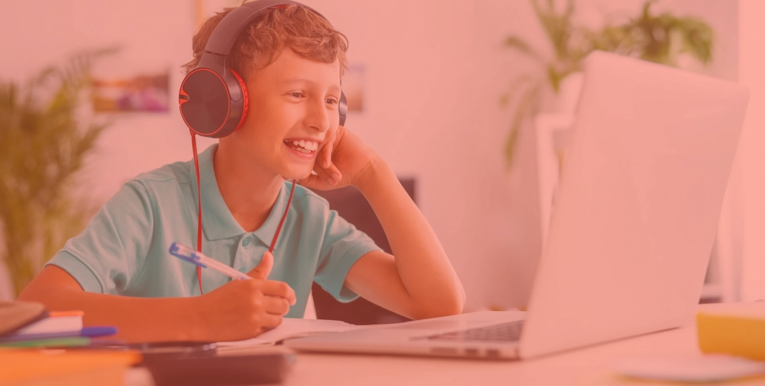 Smiling young boy wearing headphones using a laptop for remote learning at home