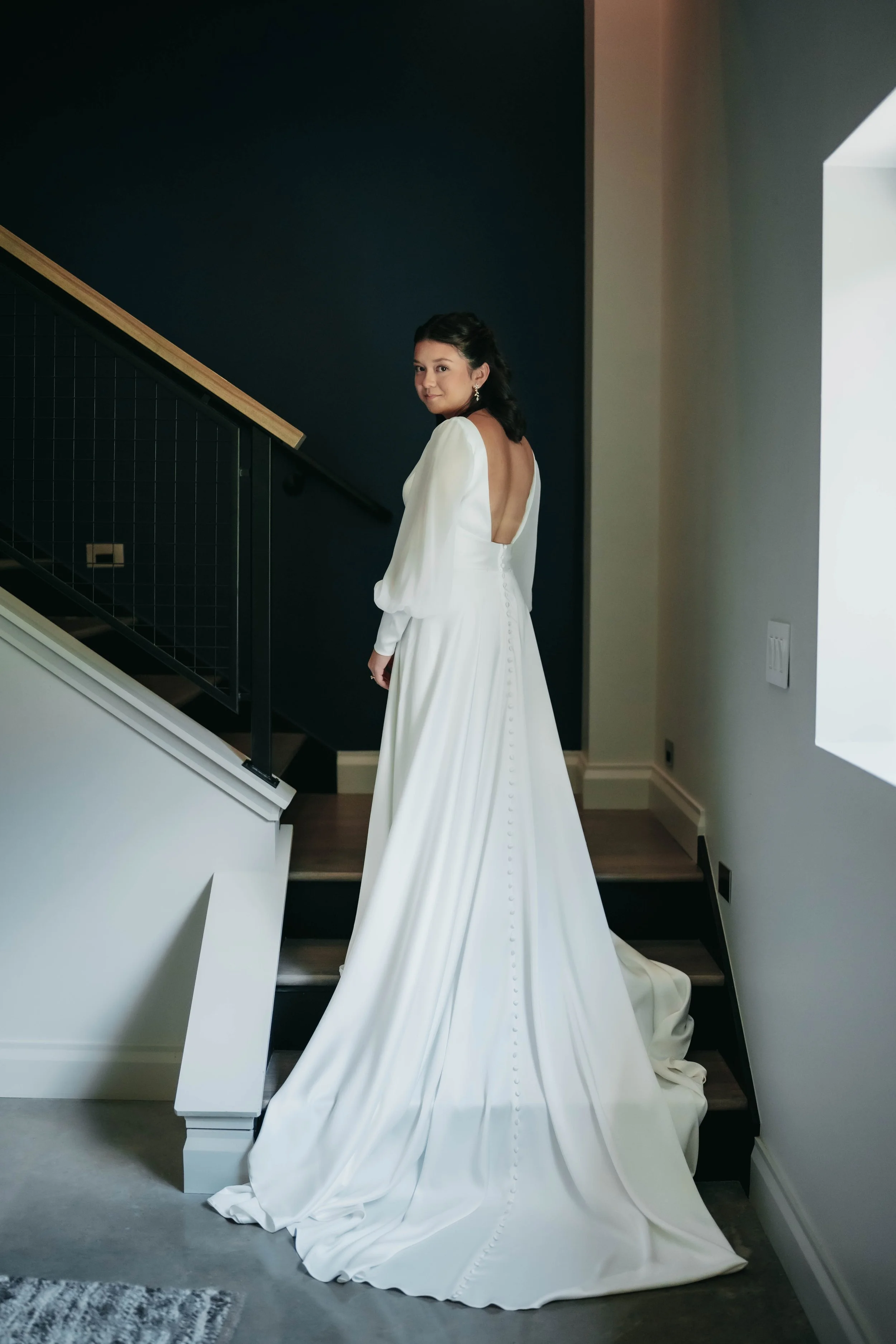 A woman in a white wedding gown standing on a staircase