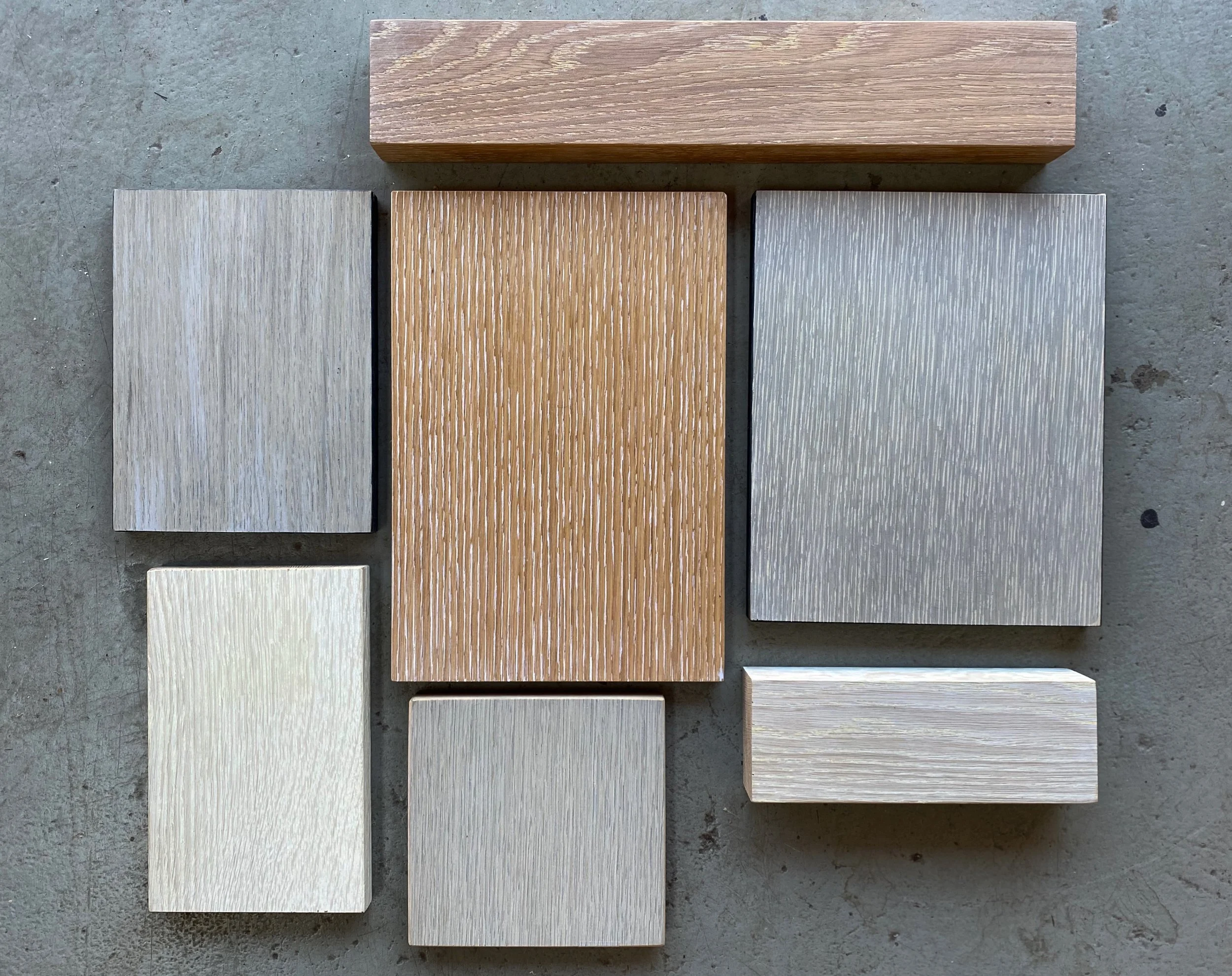 Collection of eight wooden blocks with different sizes and finishes arranged on a concrete surface.