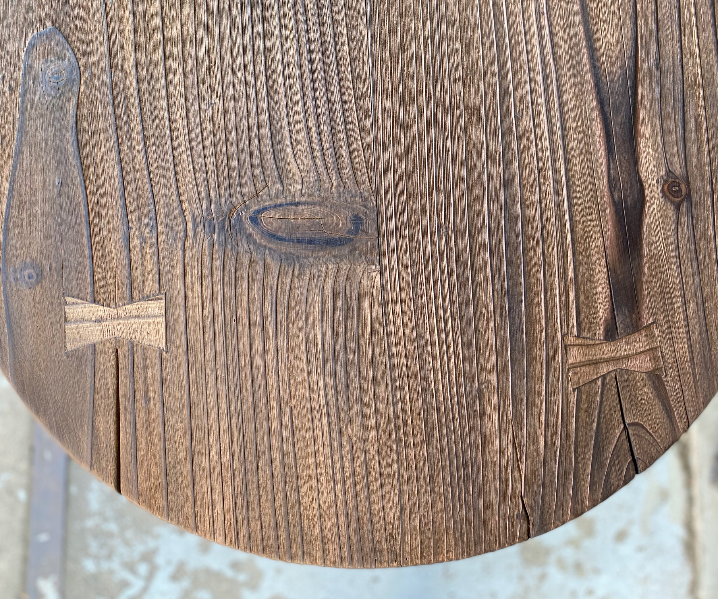 Close-up of a round wooden surface with visible grain, knots, and a large crack.