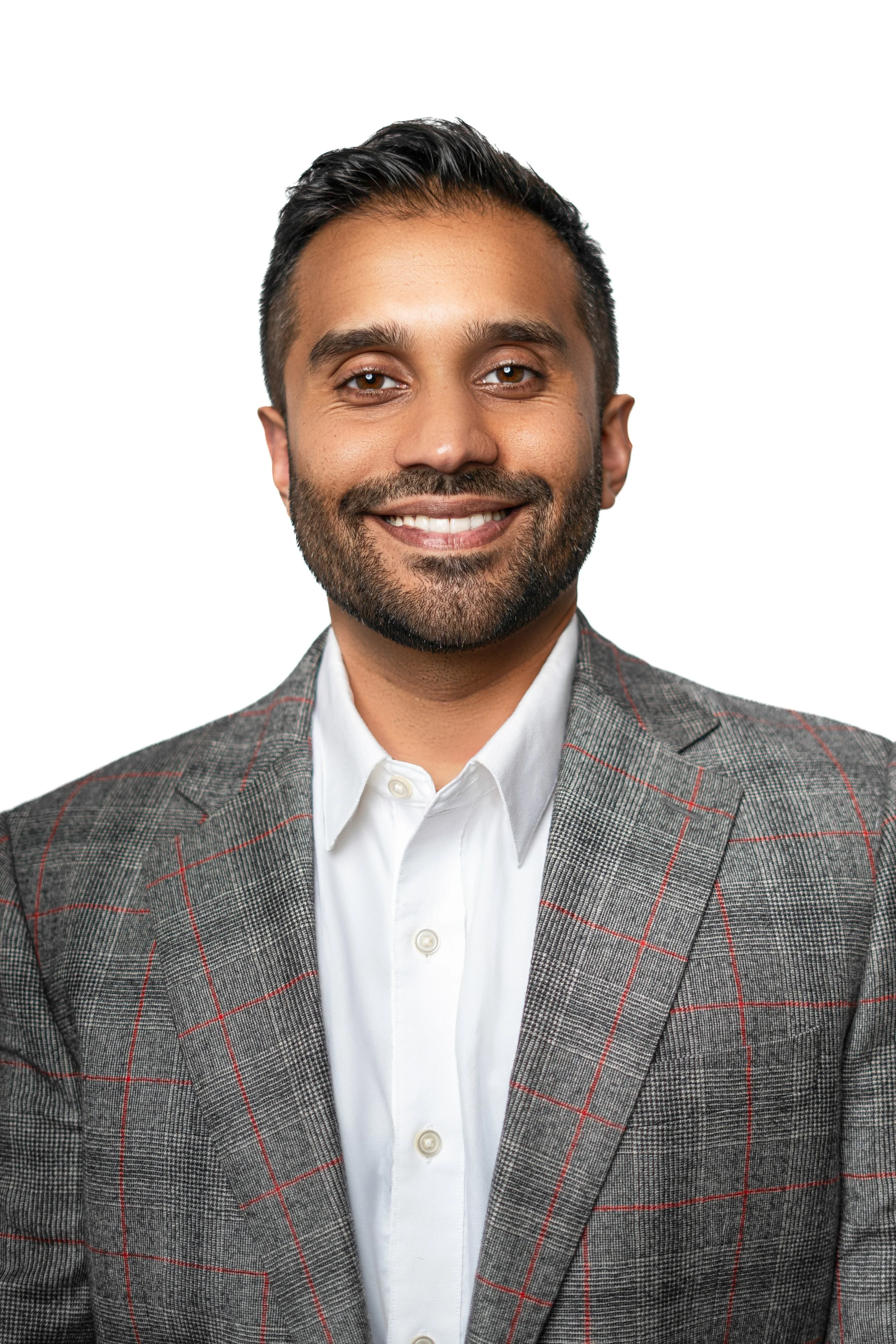 Smiling man in a plaid blazer and white shirt against white background.