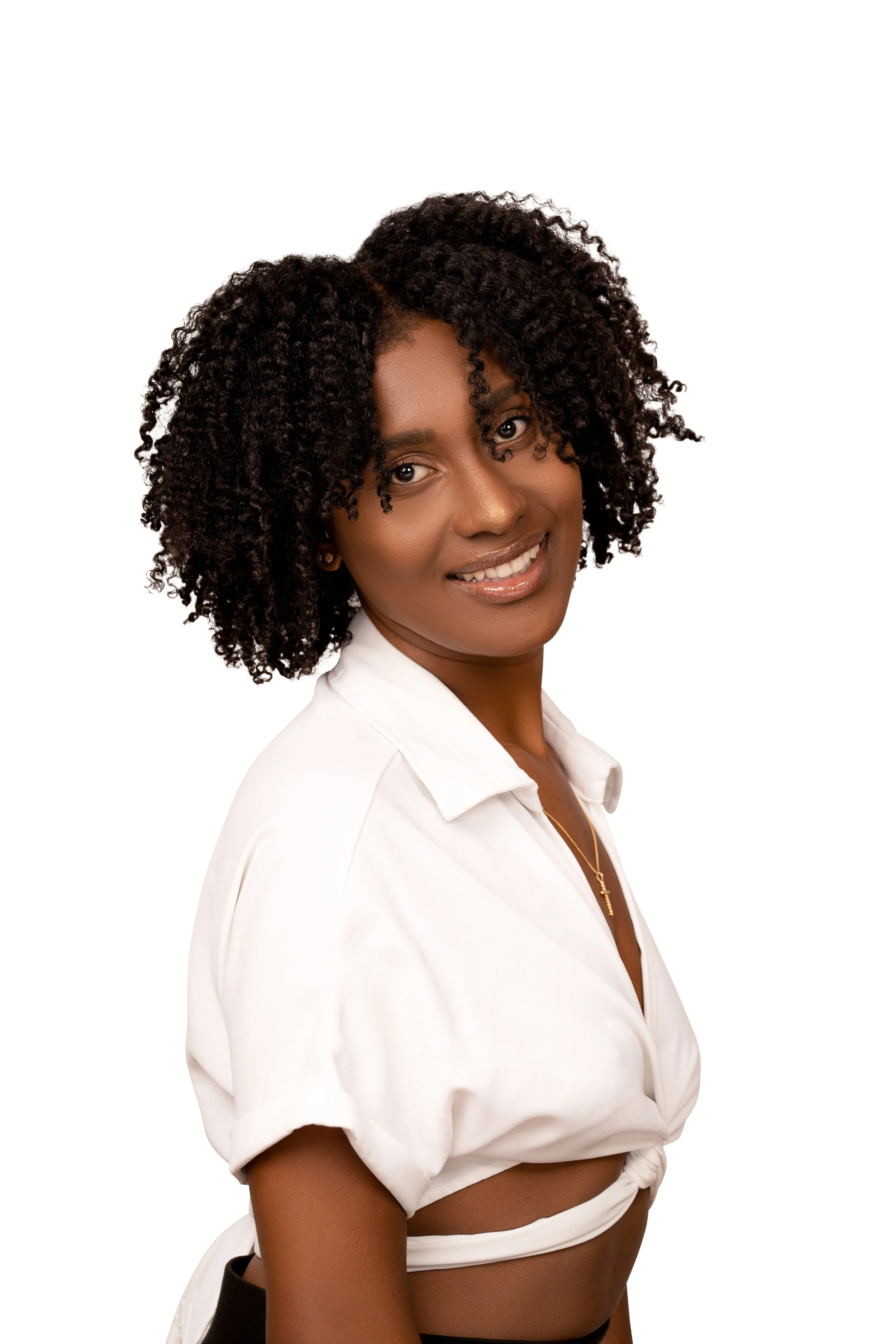 Smiling person with curly hair, wearing a white top, against a plain background.