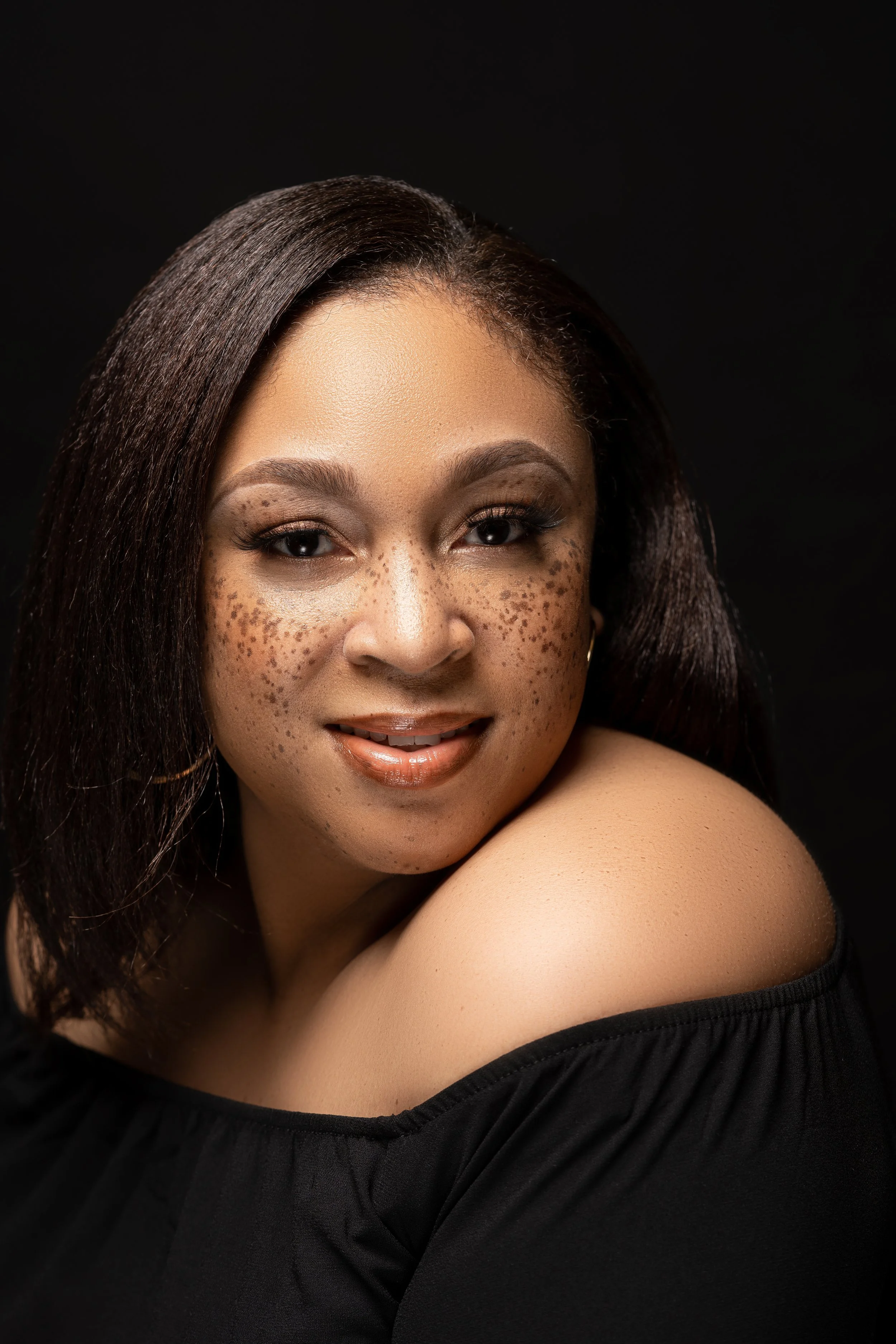 Smiling woman with freckles against a black background