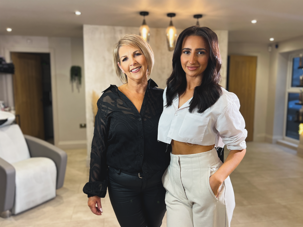 Two women standing together in a modern, well-lit living room, smiling at the camera.