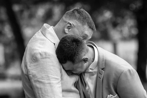 deux hommes s'enlacent habillés en marié