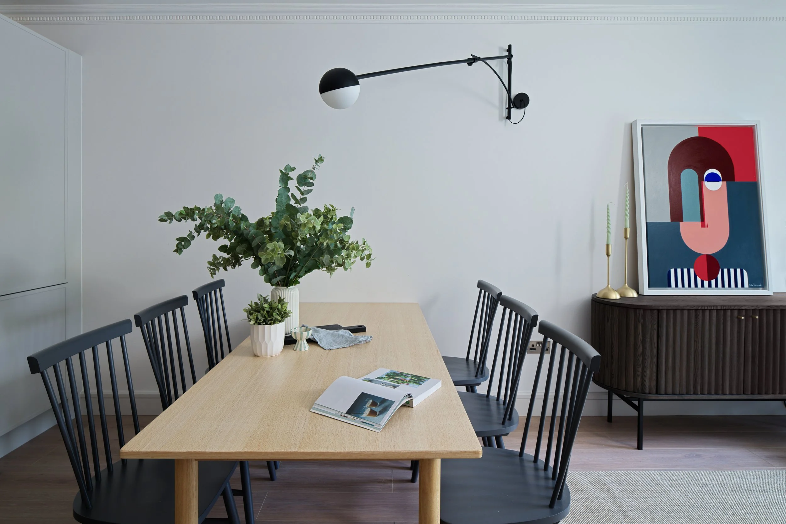 oak dining table with indigo coloured dining chairs and artwork