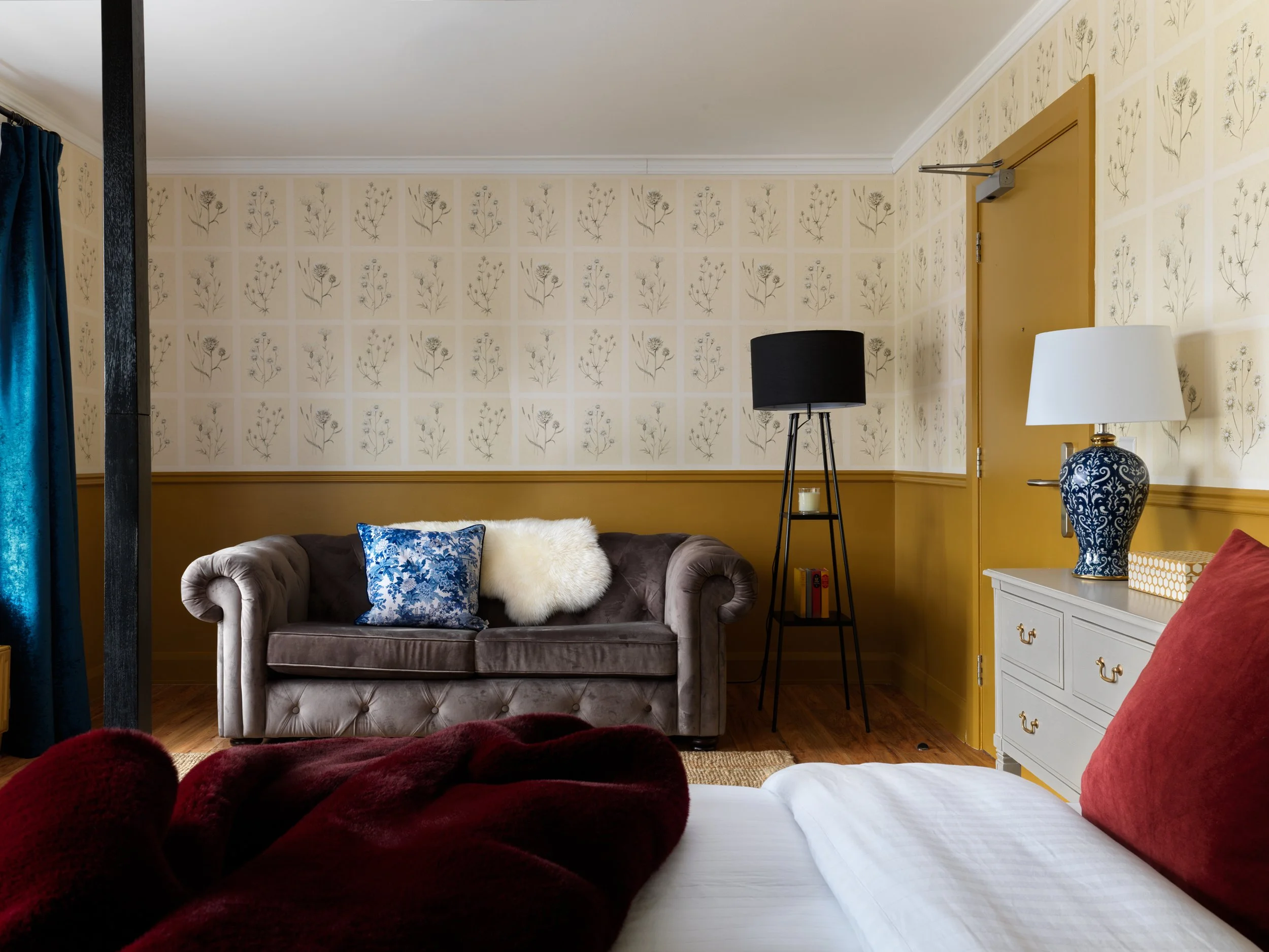 contemporary hotel bedroom with mustard panelling and large sofa