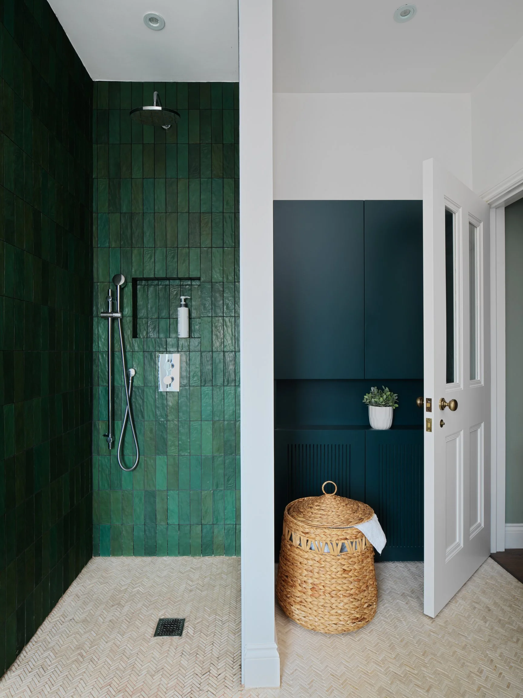 green shower with stone coloured floor tiles and rattan basket
