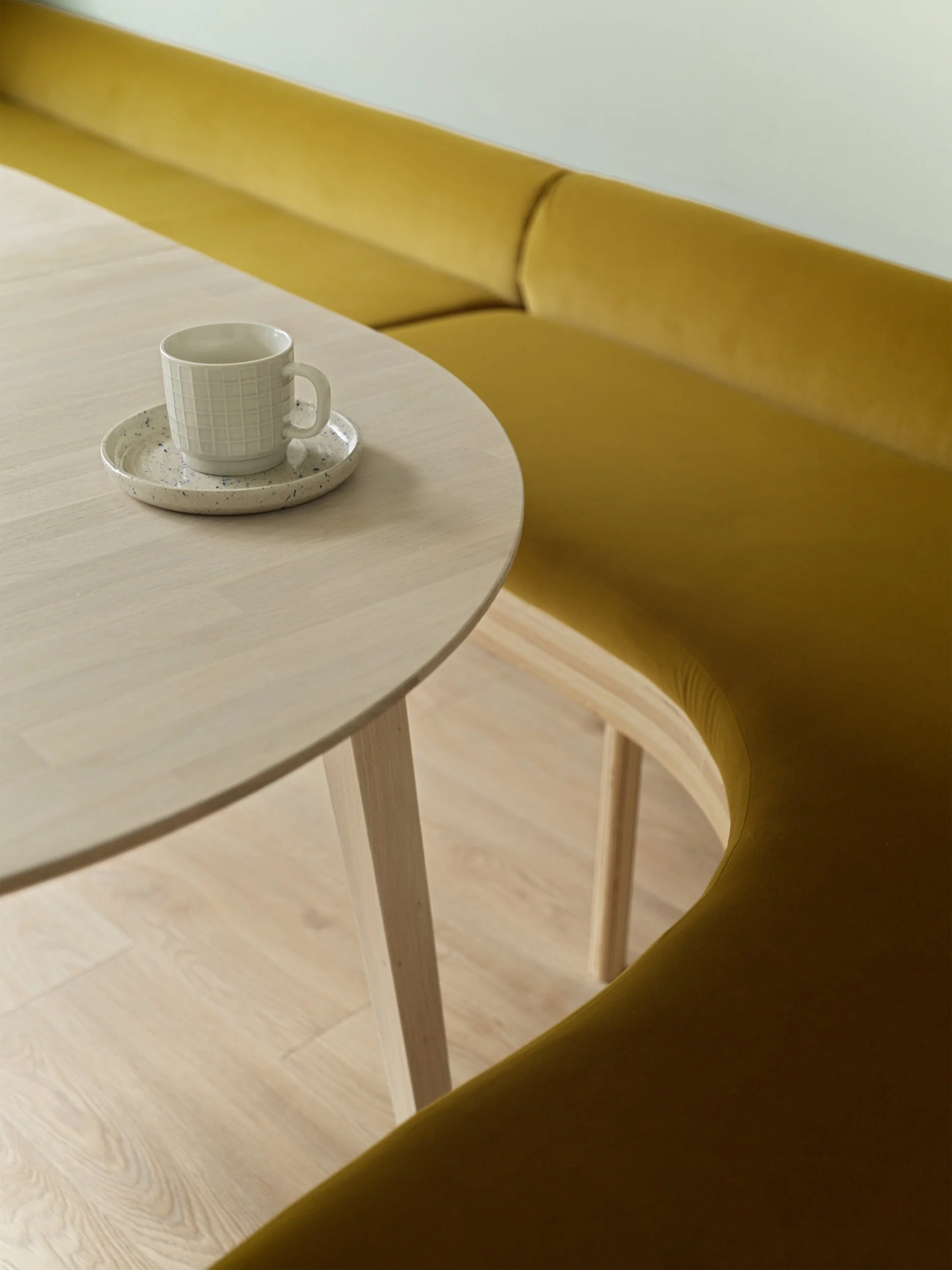 yellow curved seating bench with oak table