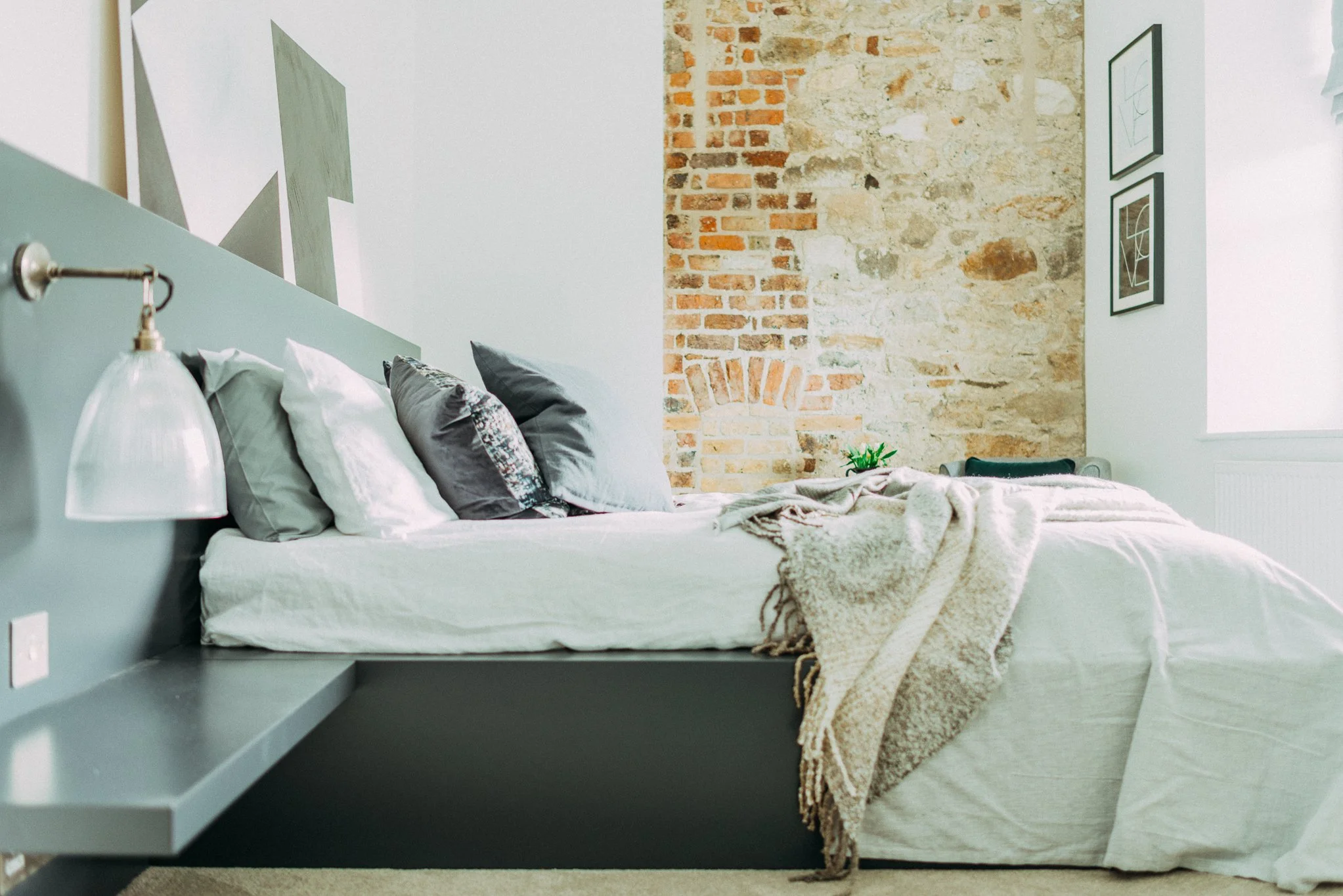 teal double bed with brick wall