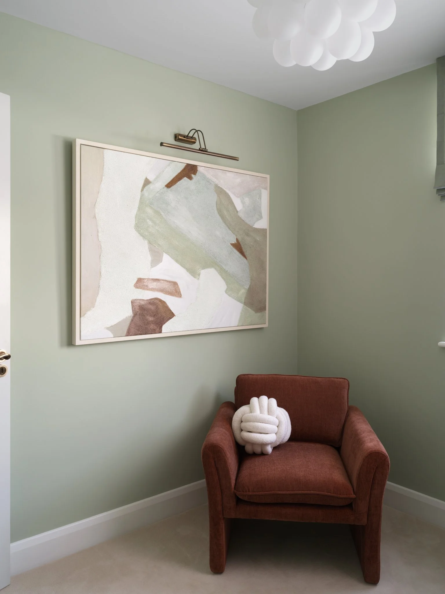 sage interior design with rust colour armchair and contemporary artwork