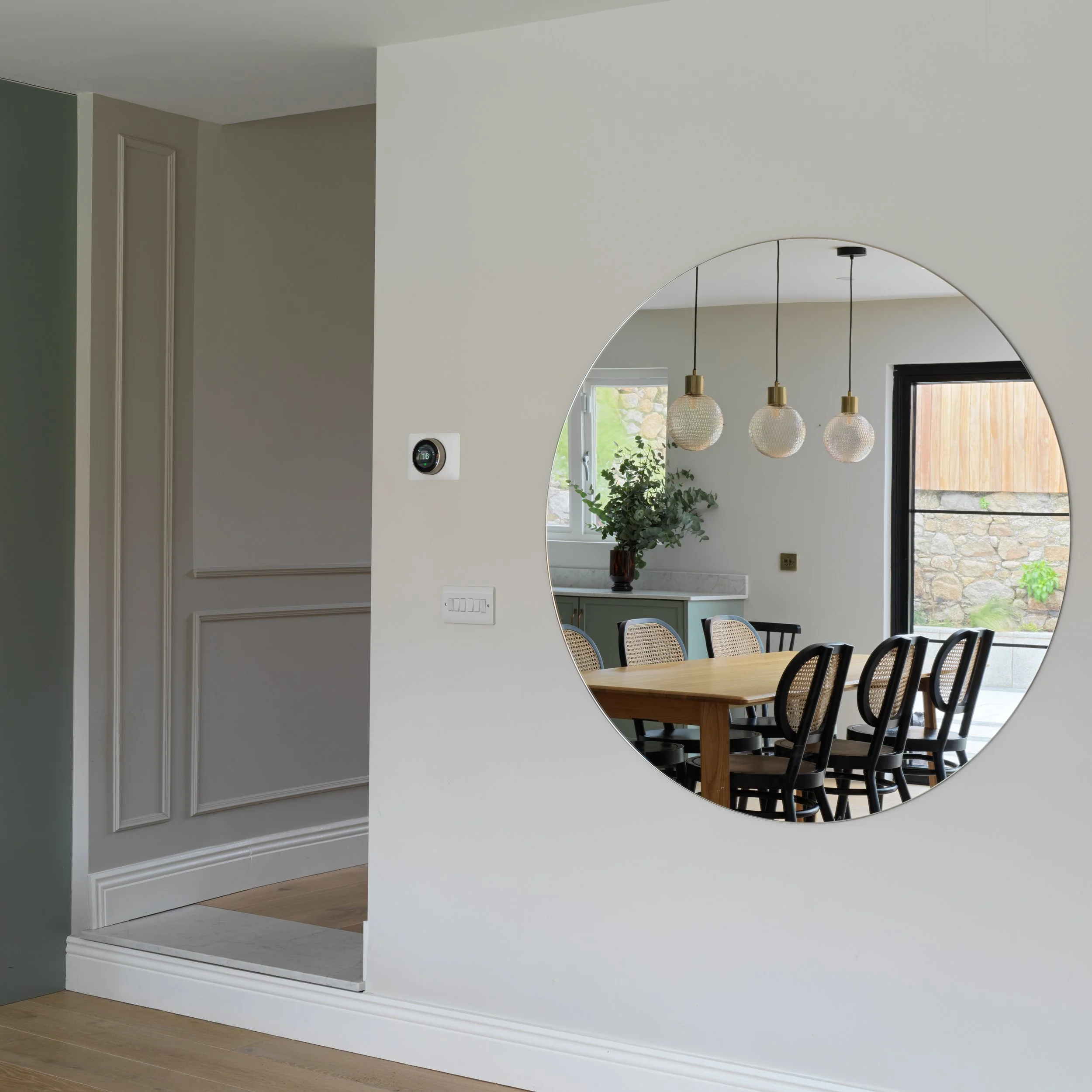 large circular mirror reflecting dining area