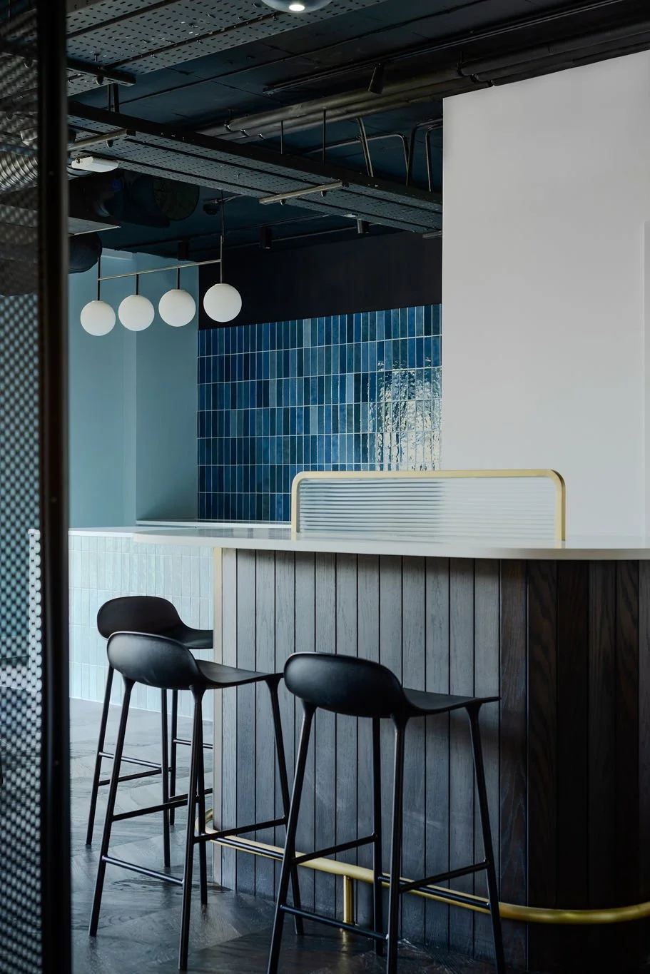 black curved counter top with blue tiled kitchen space