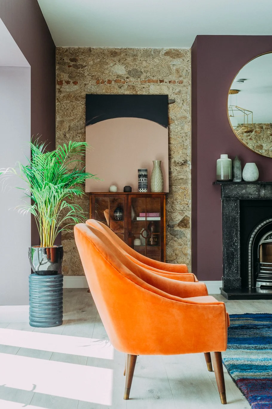 stone and plum wall with orange arm chair