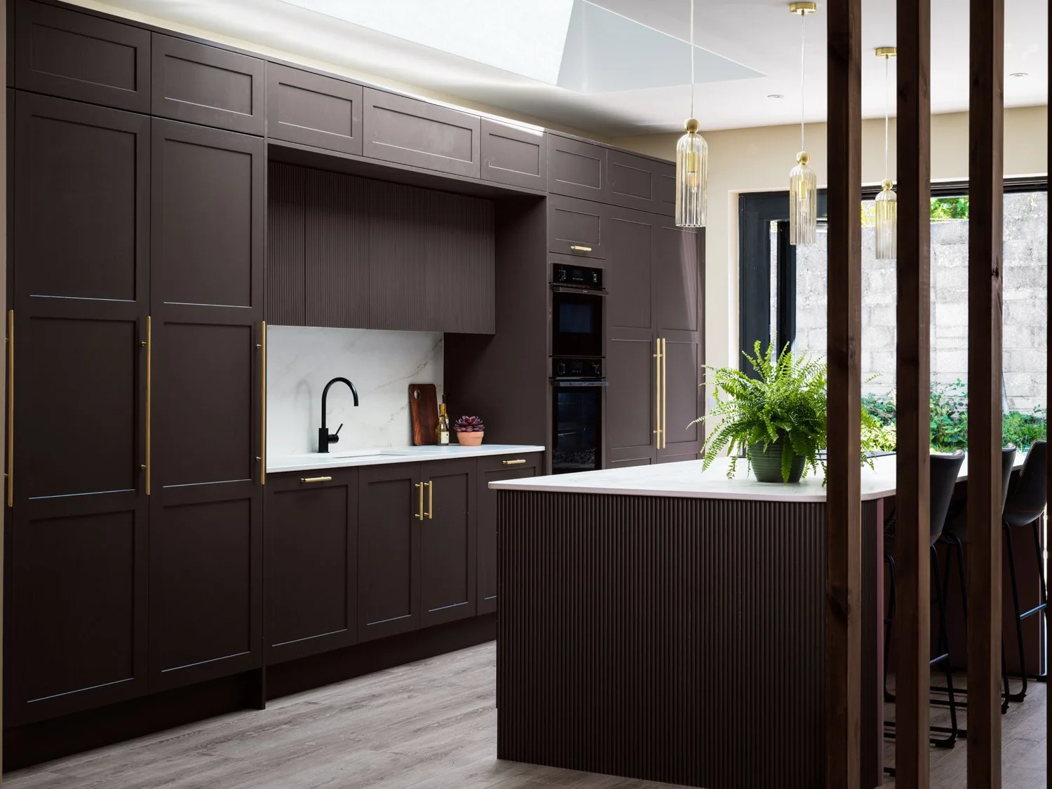 brown kitchen cabinetry with gold handles and marble backsplash