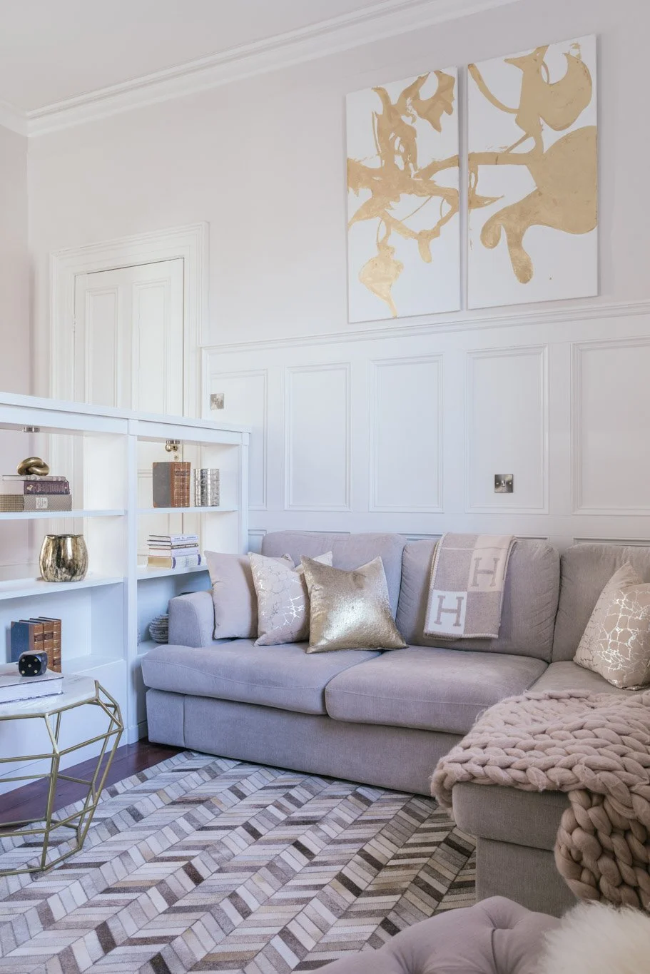 violet sofa in an alcove with white & gold artwork
