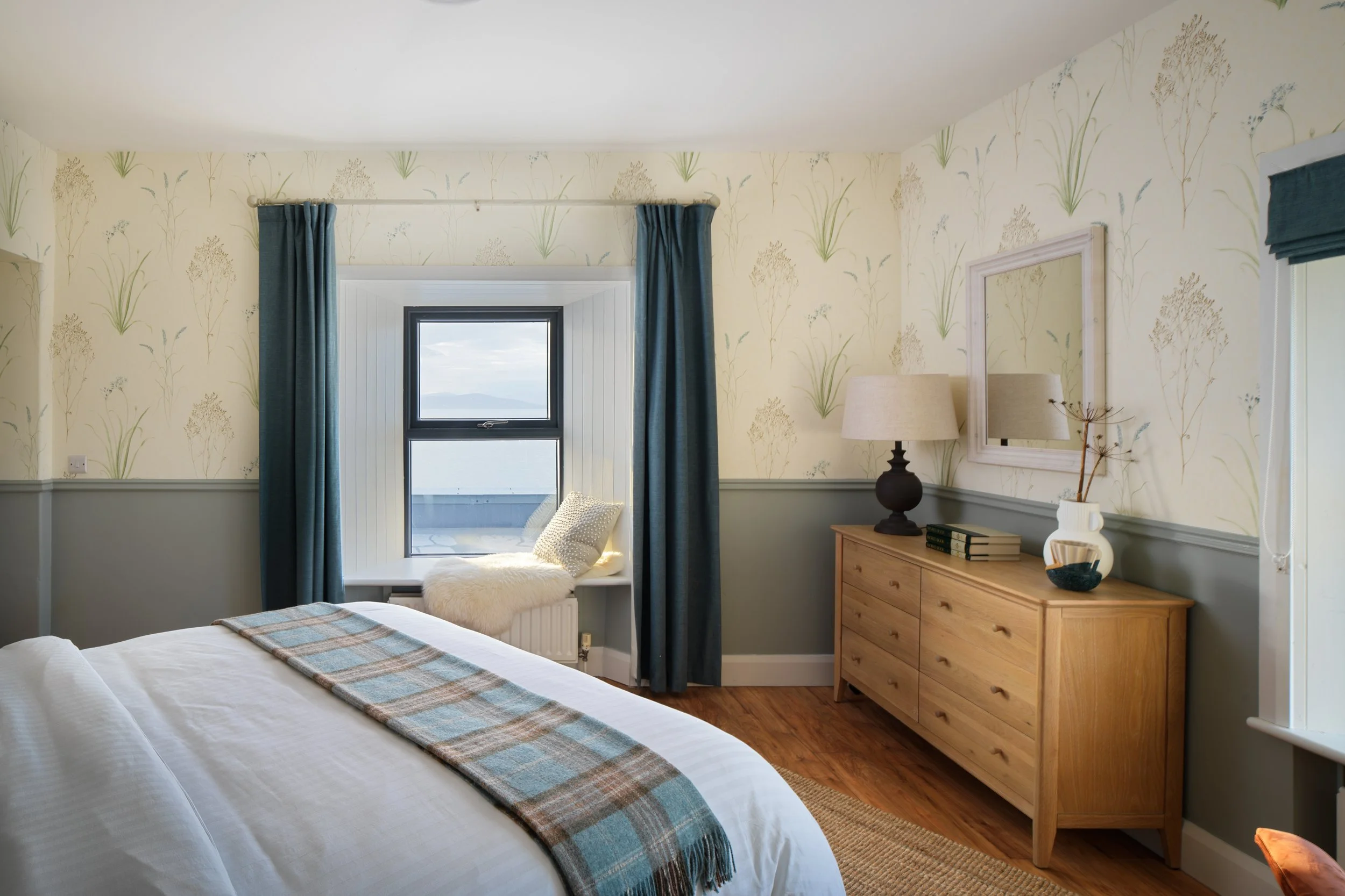 contemporary hotel bedroom with oak dresser and sea views