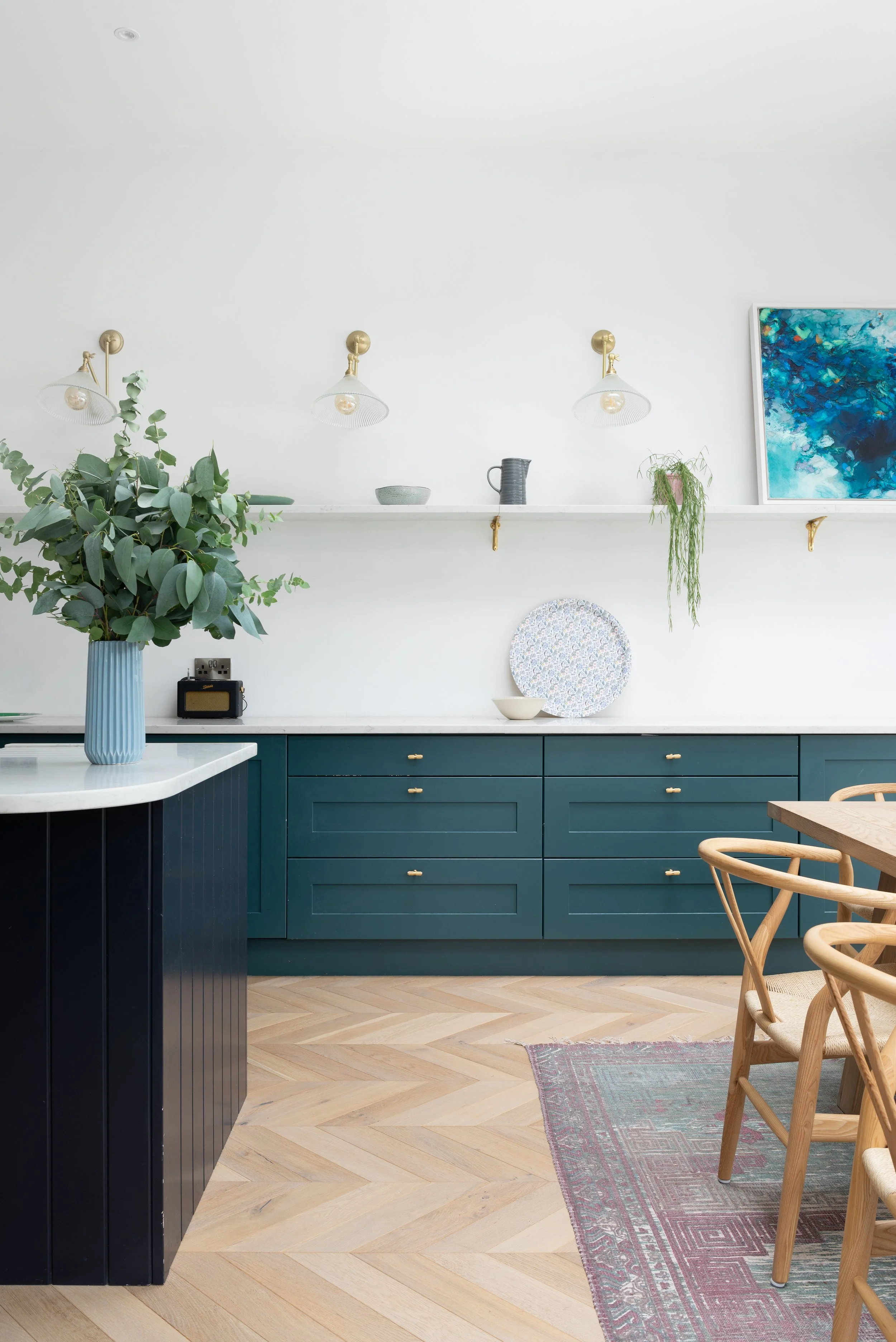 white kitchen with teal cabinetry and oak dining chairs