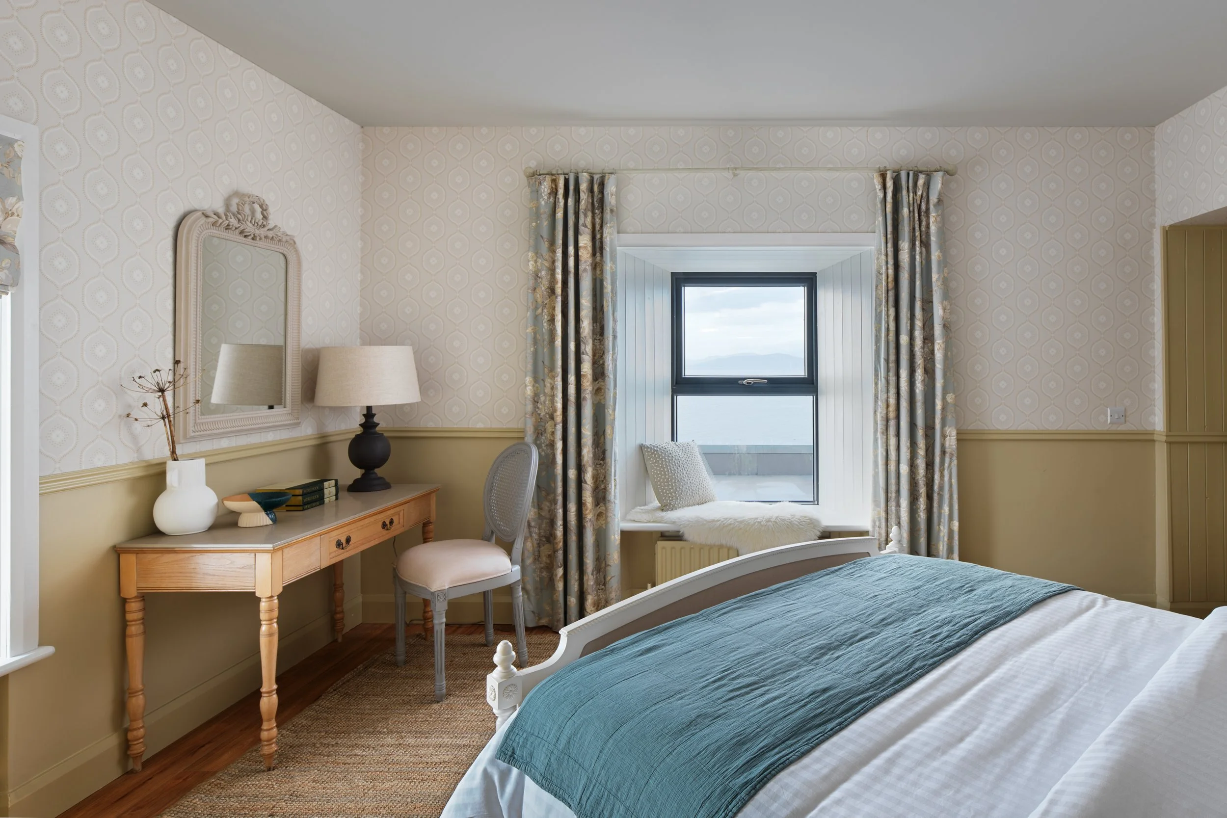 contemporary hotel bedroom with blue throw and sea views