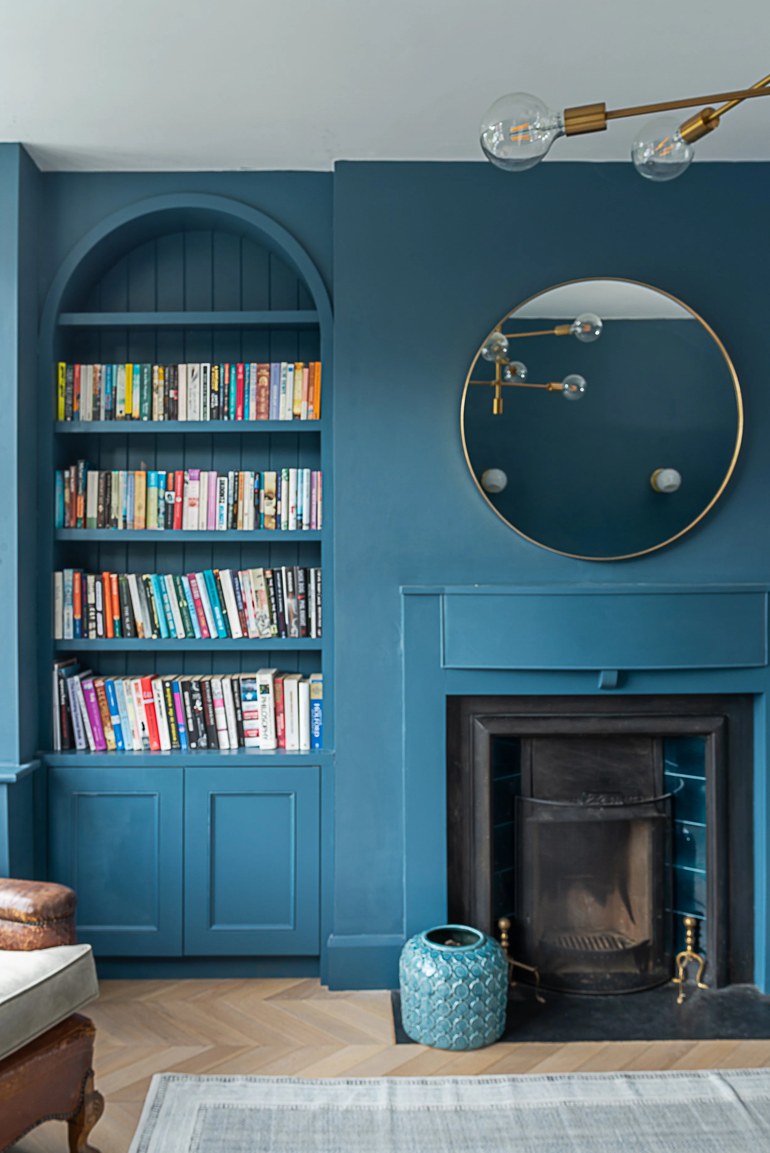 blue cabinetry and fireplace with large circular mirror on wall