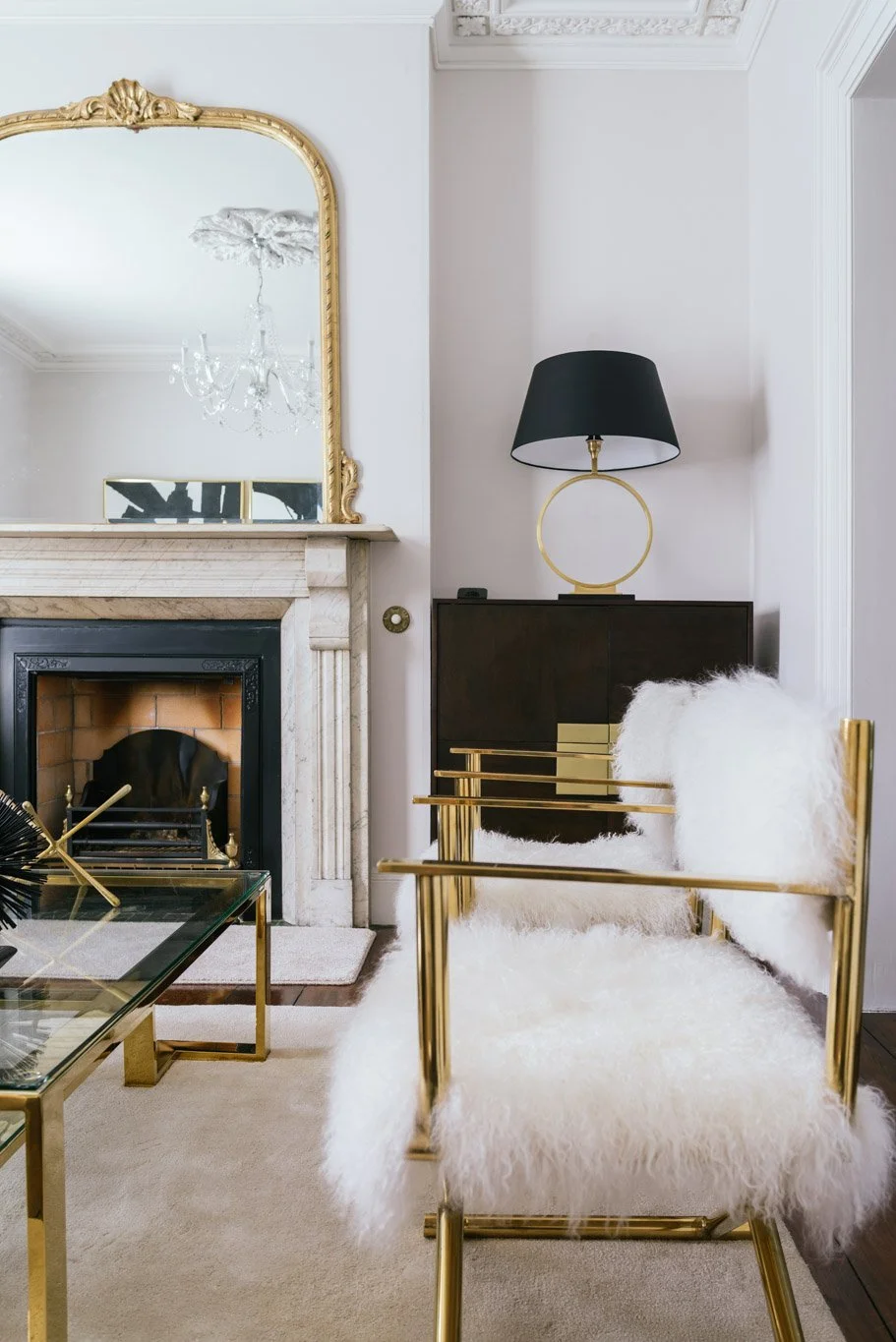 white & gold arm chair with gold mirror by fireplace