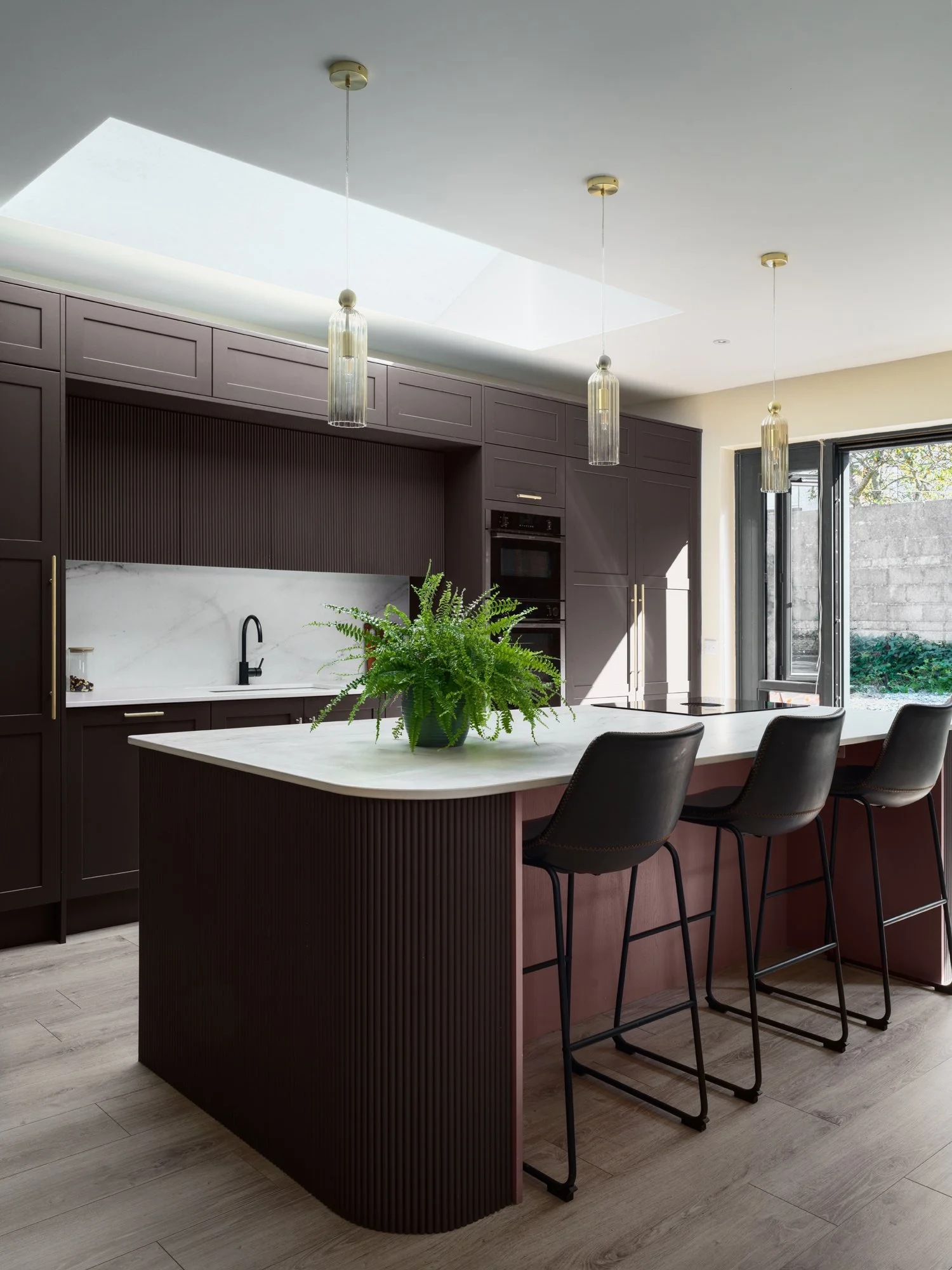 brown kitchen cabinetry with gold handles and marble backsplash