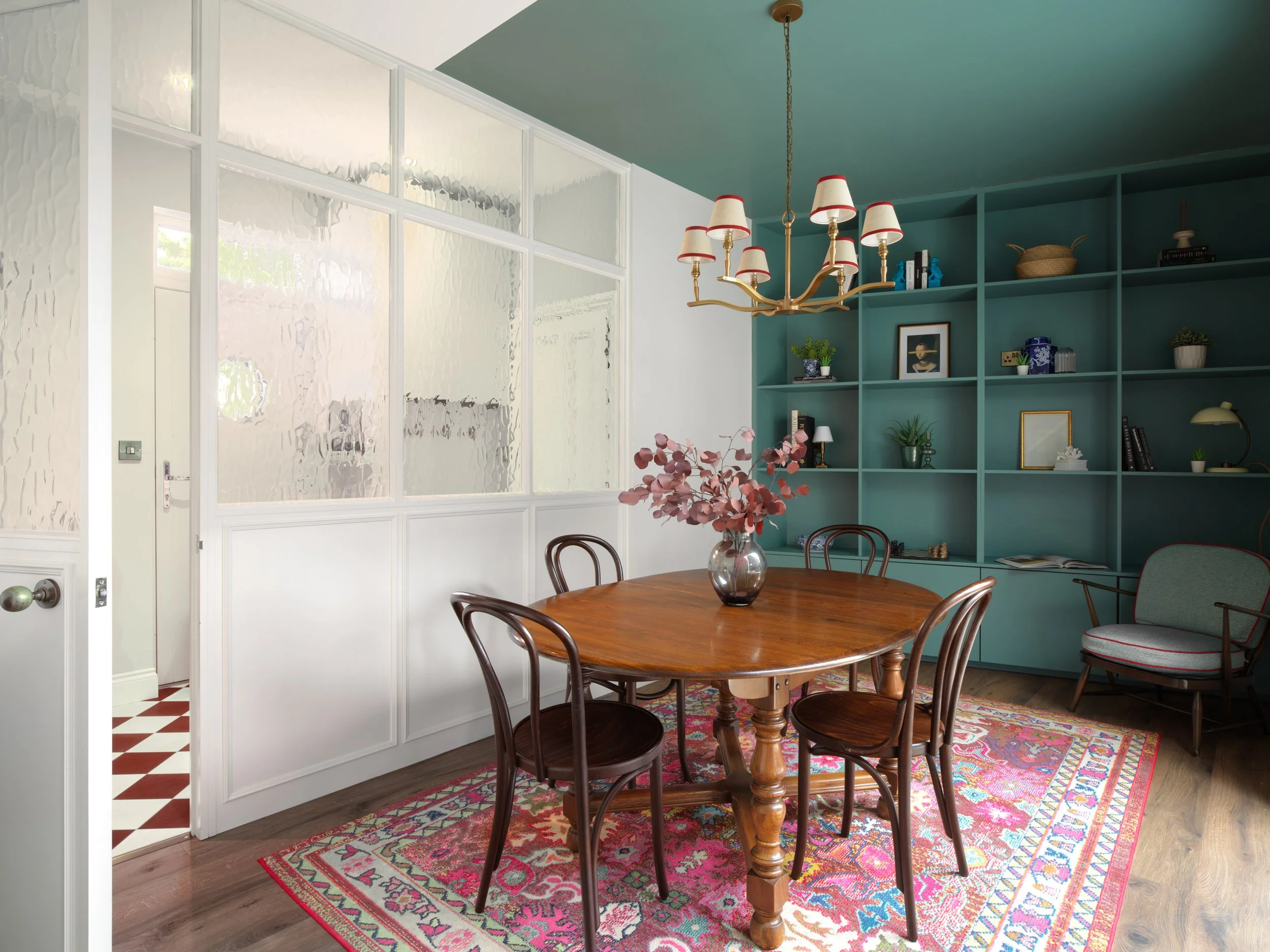 green cabinetry in dining area with old mahogany dining table and red rug