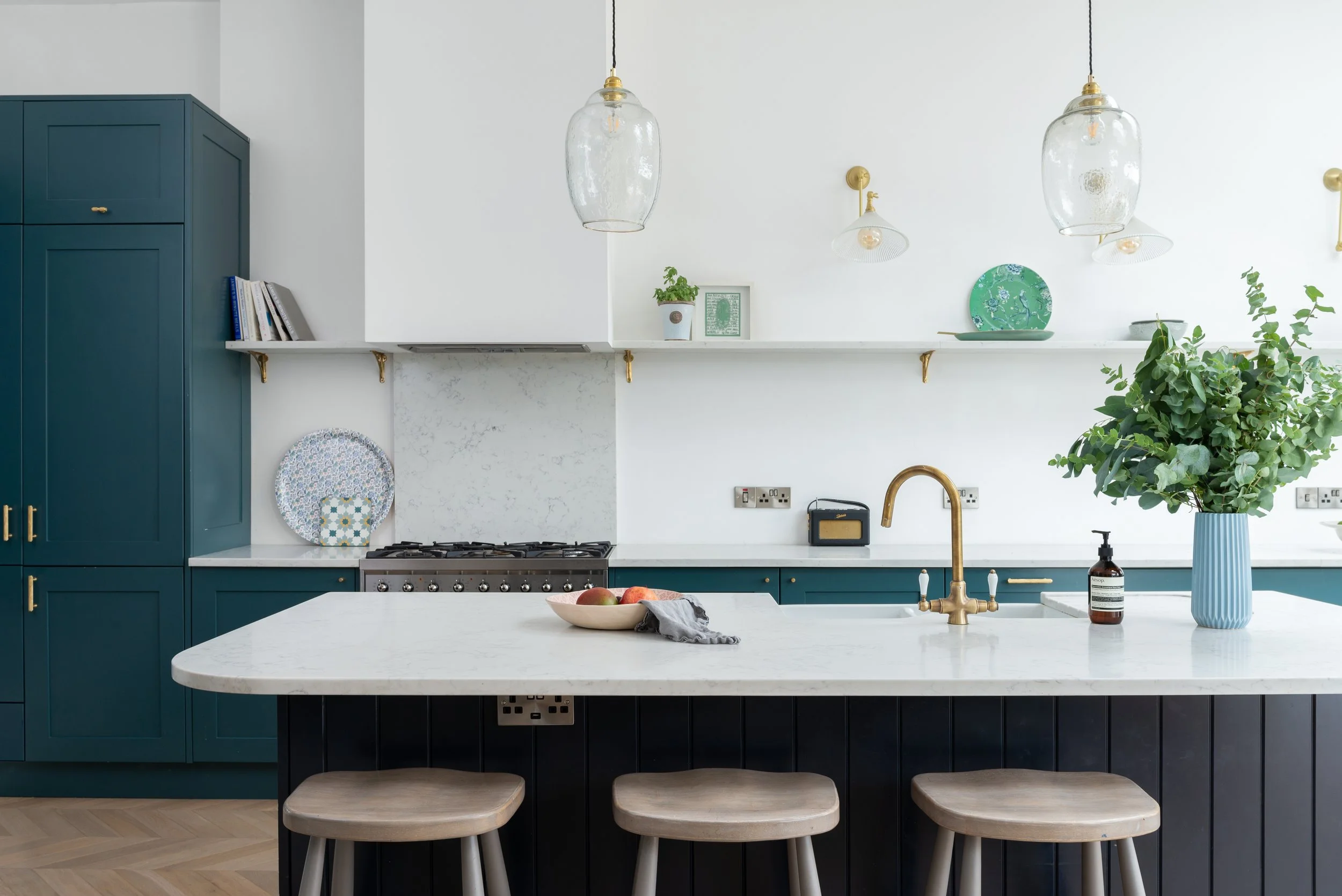white kitchen with teal cabinetry and gold pendants