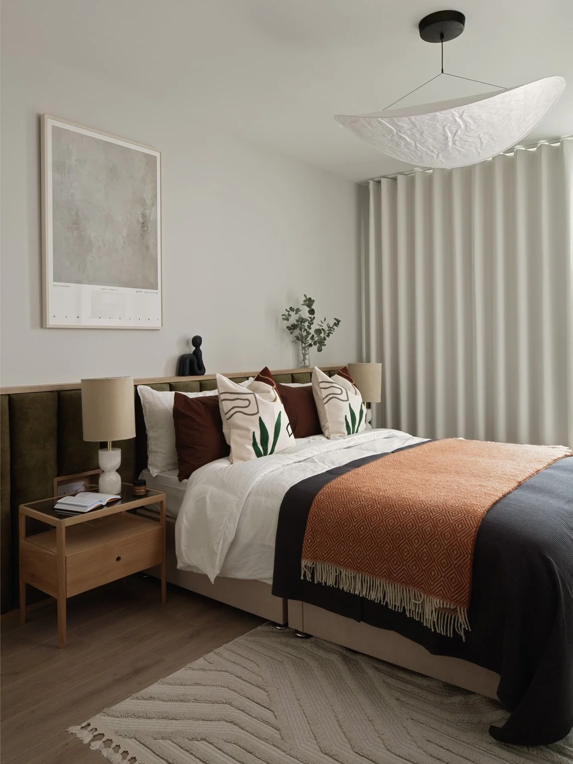 cream interior designed bedroom with artwork on wall and rust coloured bed throw