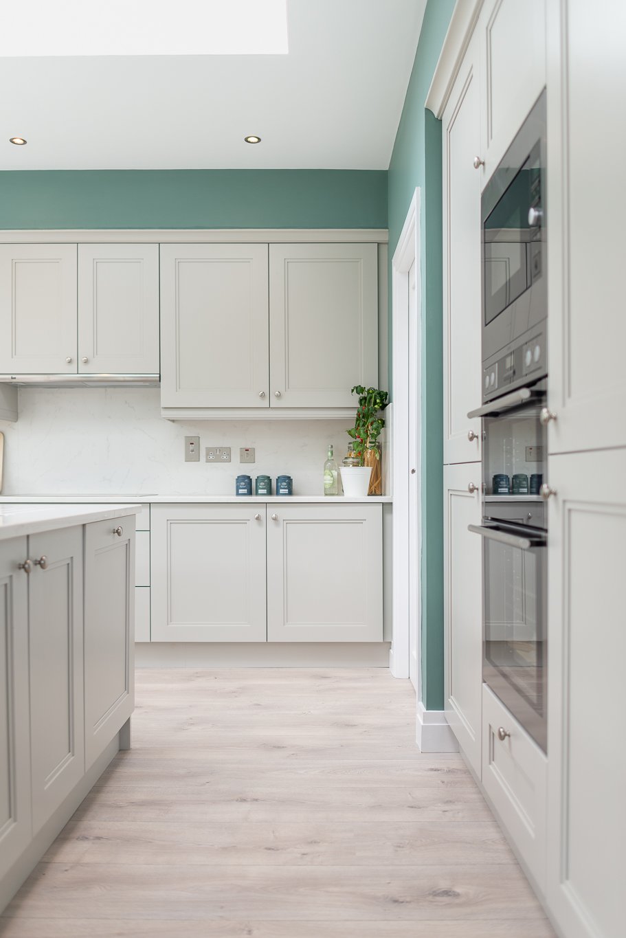 kitchen area with light teal walls and white cabinetry