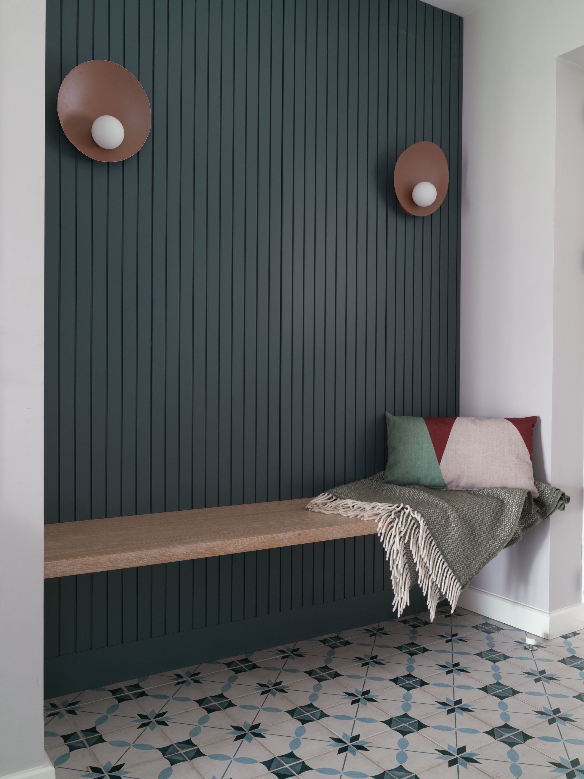 patterned floor tiles with teal wall panelling in hallway 