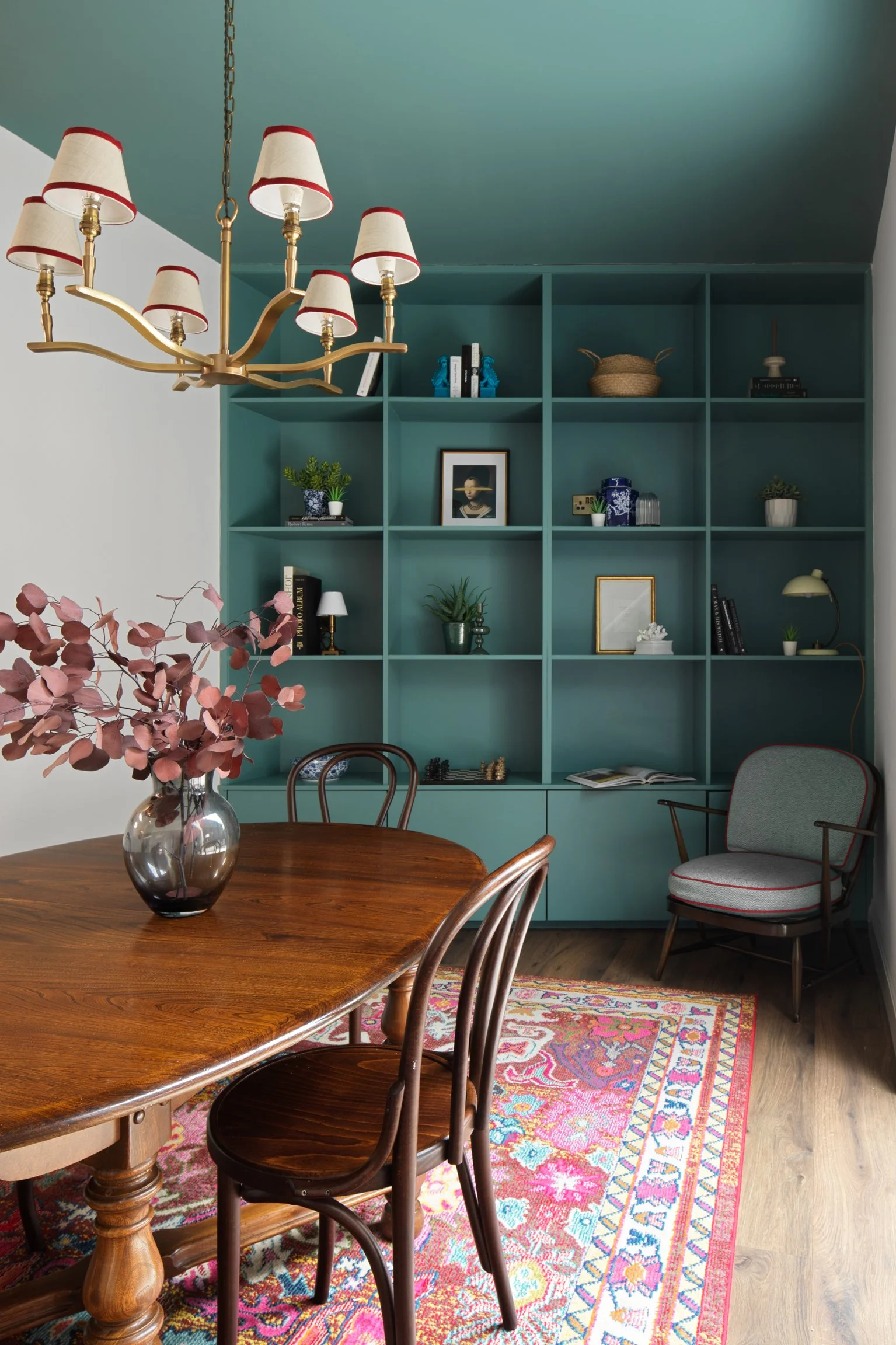 green cabinetry in dining area with old mahogany dining table and red rug