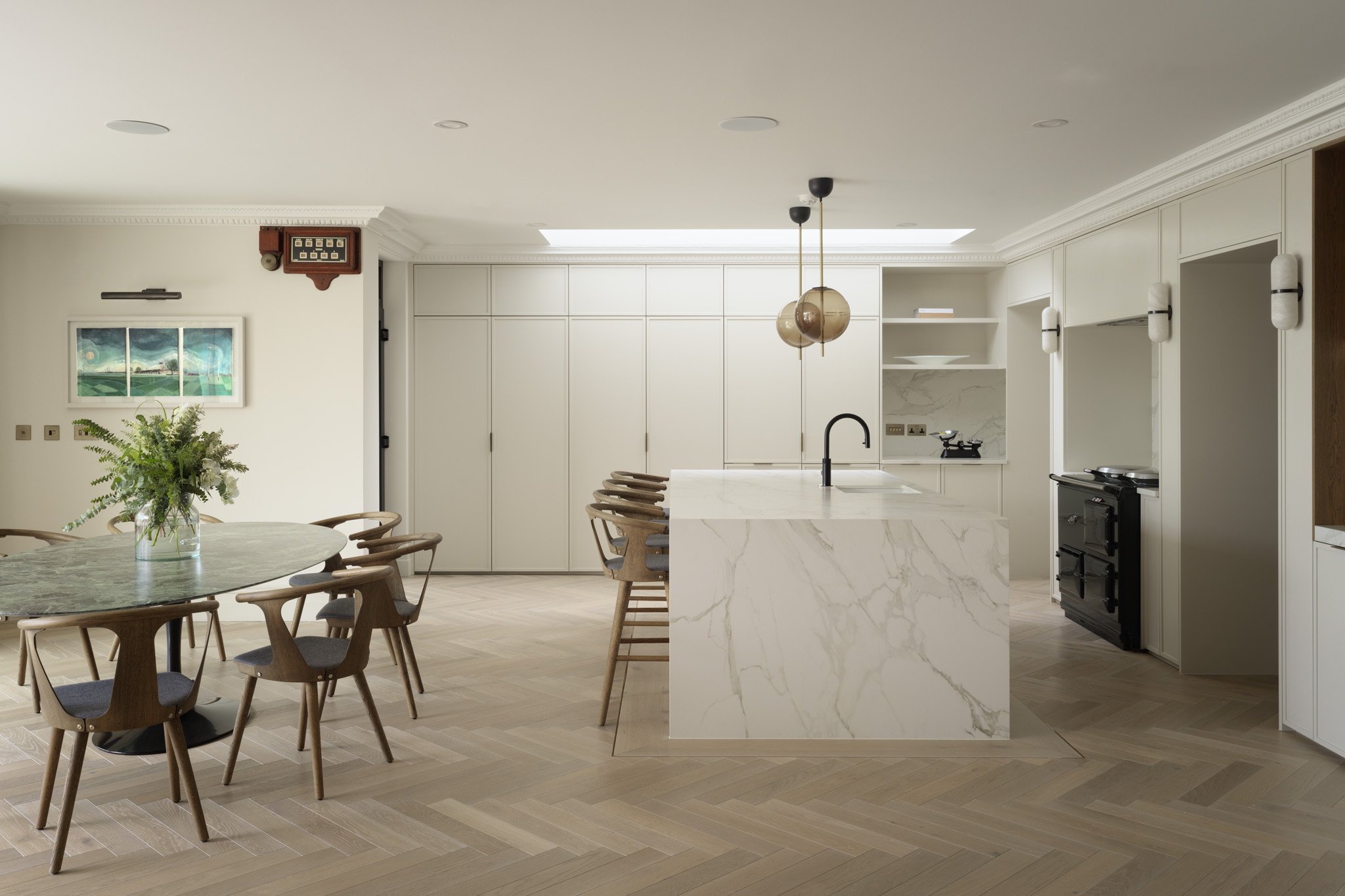 Modern kitchen with marble island, white cabinetry, pendant lighting, and wooden dining table with chairs.