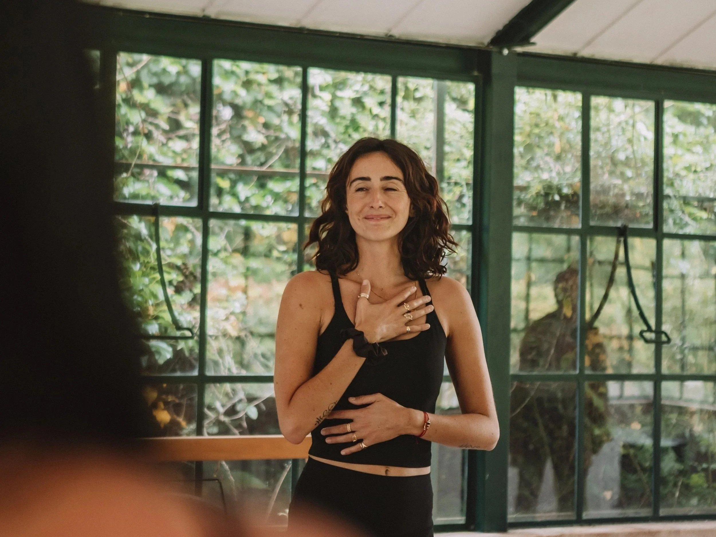 Jessi Galvin with hands on heart practising intuition and mindfulness in greenhouse studio Ericeira Portugal