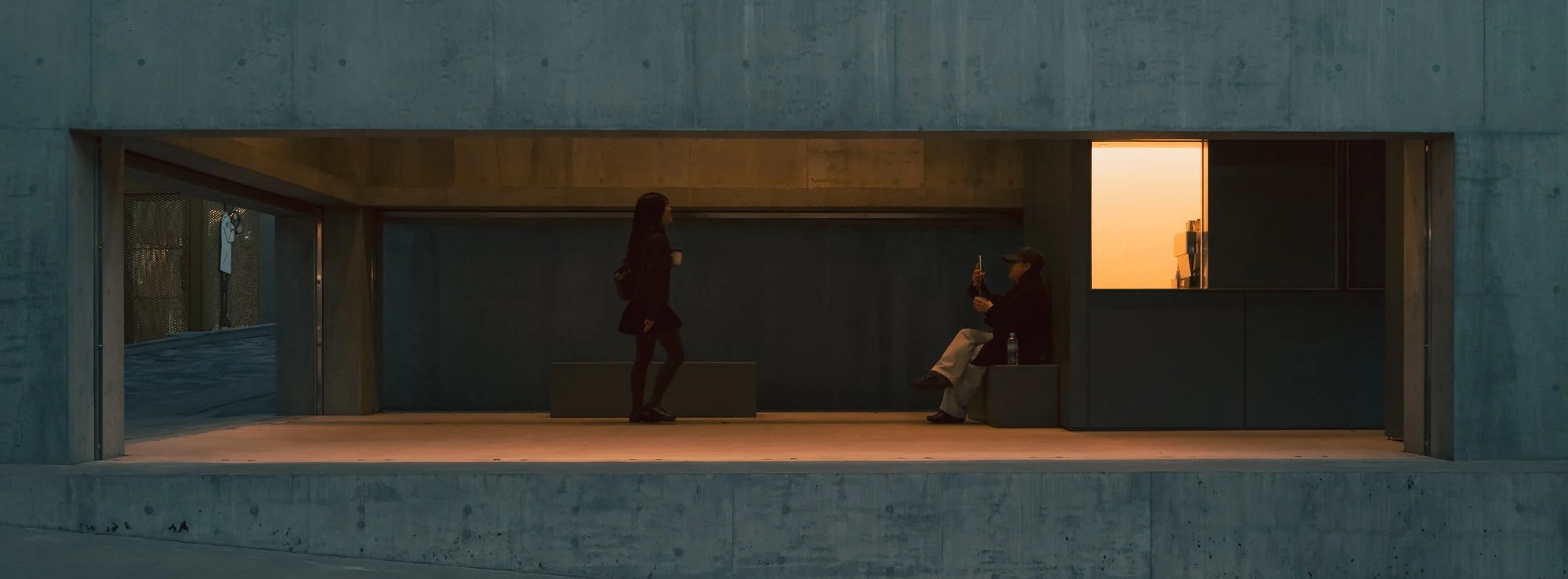 Print AD-0024. Two figures within a long horizontal opening in a concrete building.