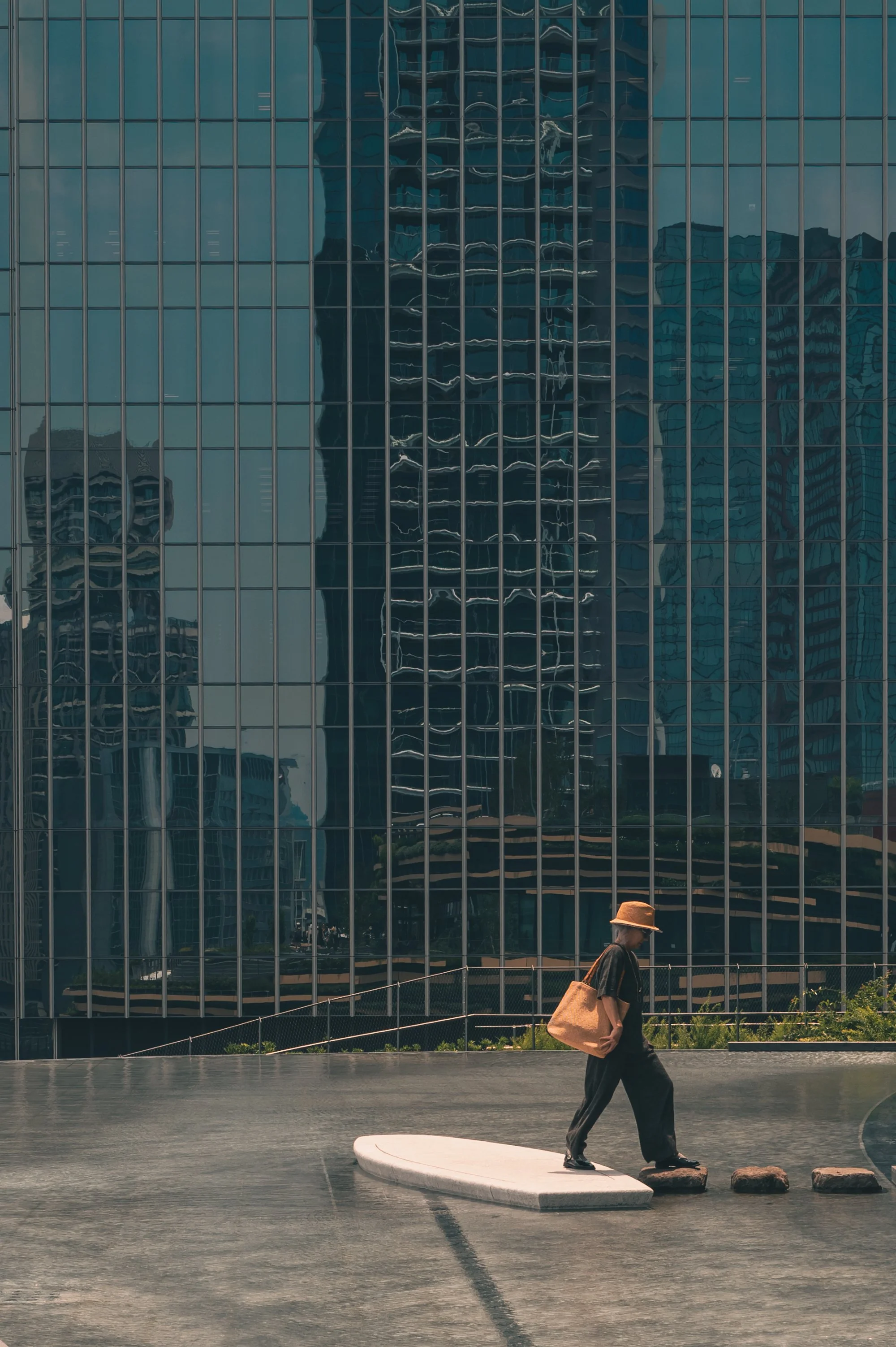 Print AD-0017. A person beside water and a reflective glass facade.