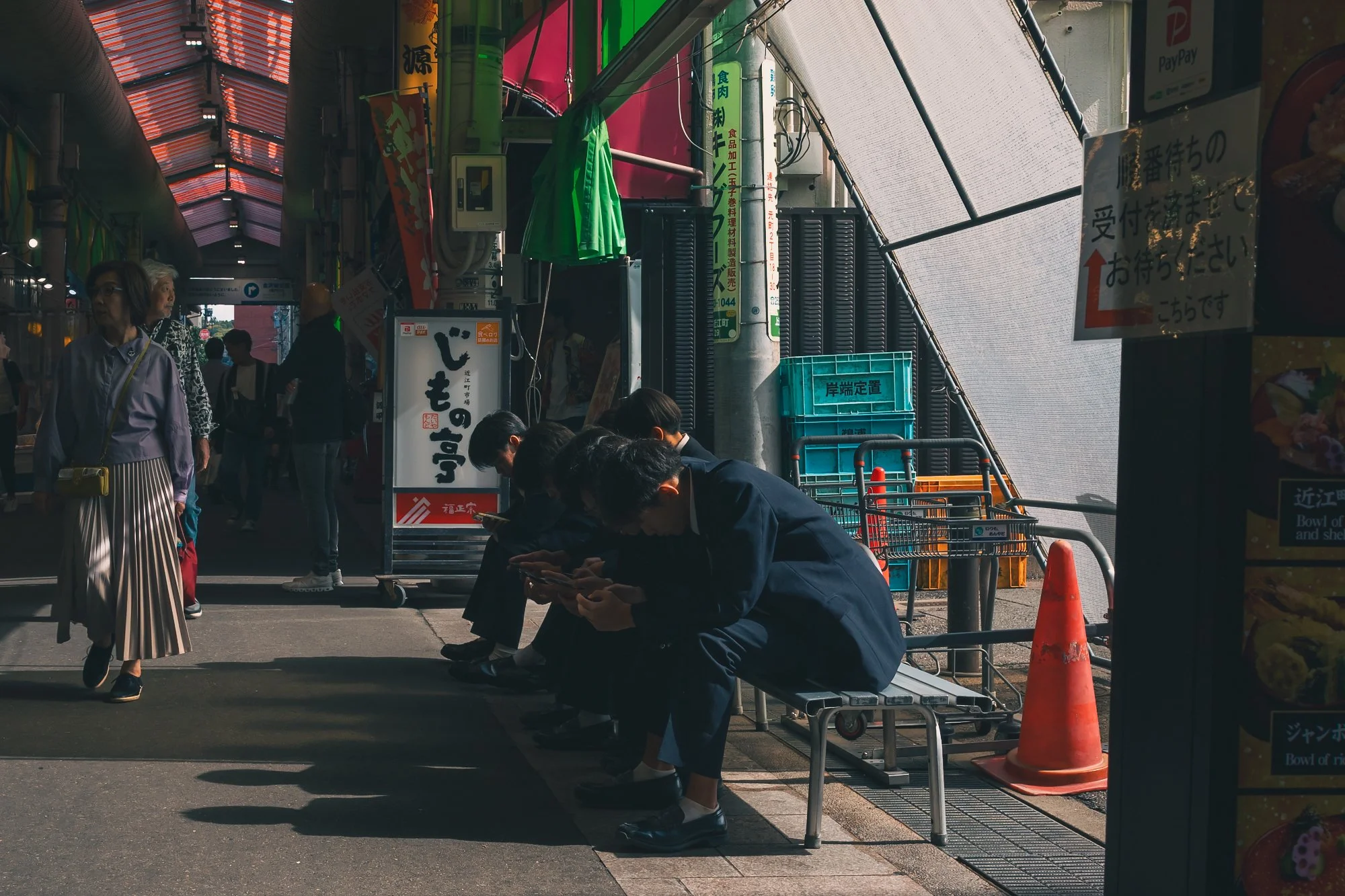 Print AD-0048. People pausing on benches in a covered shopping street.