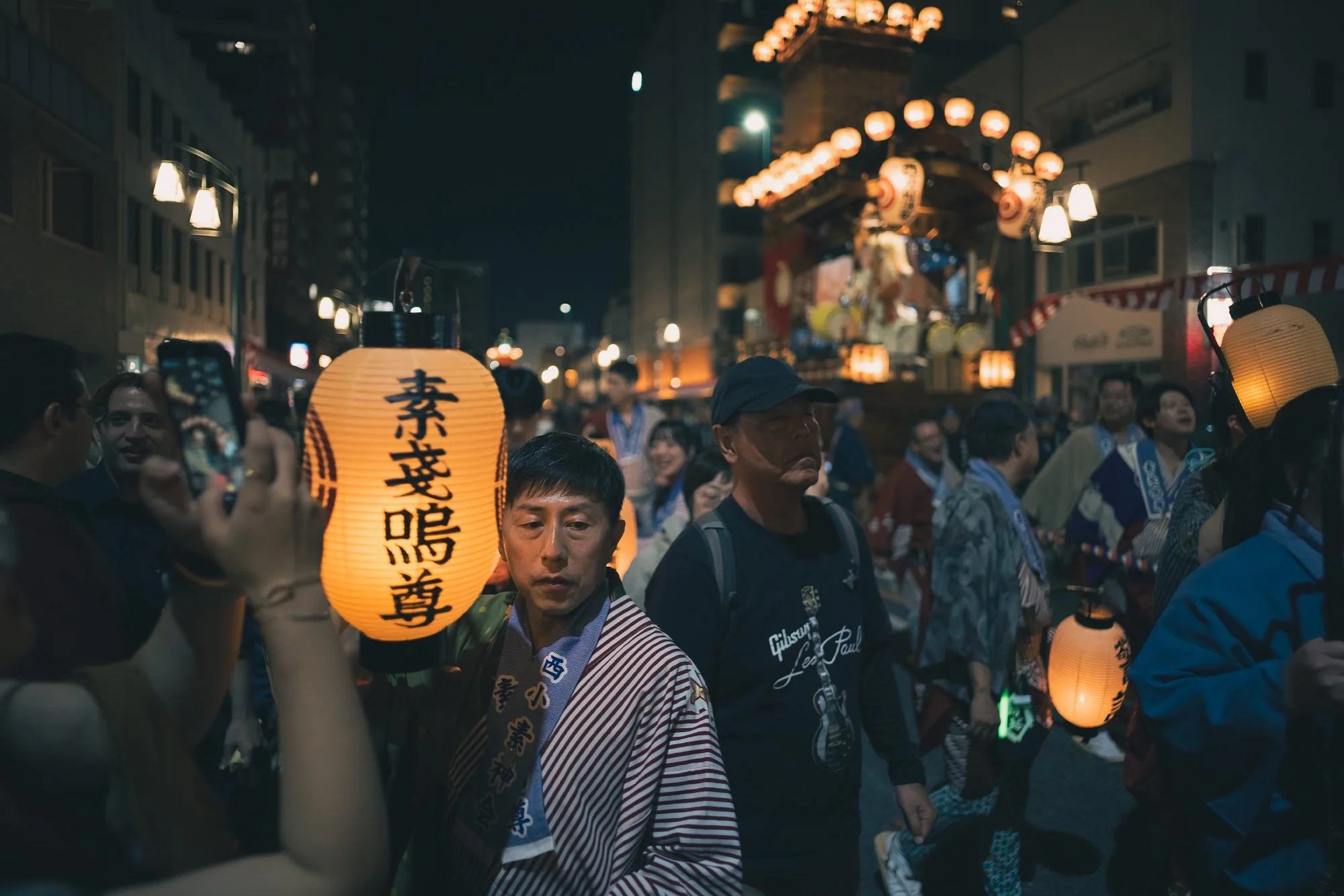 Print AD-0034. People walking beside lanterns and an illuminated float.