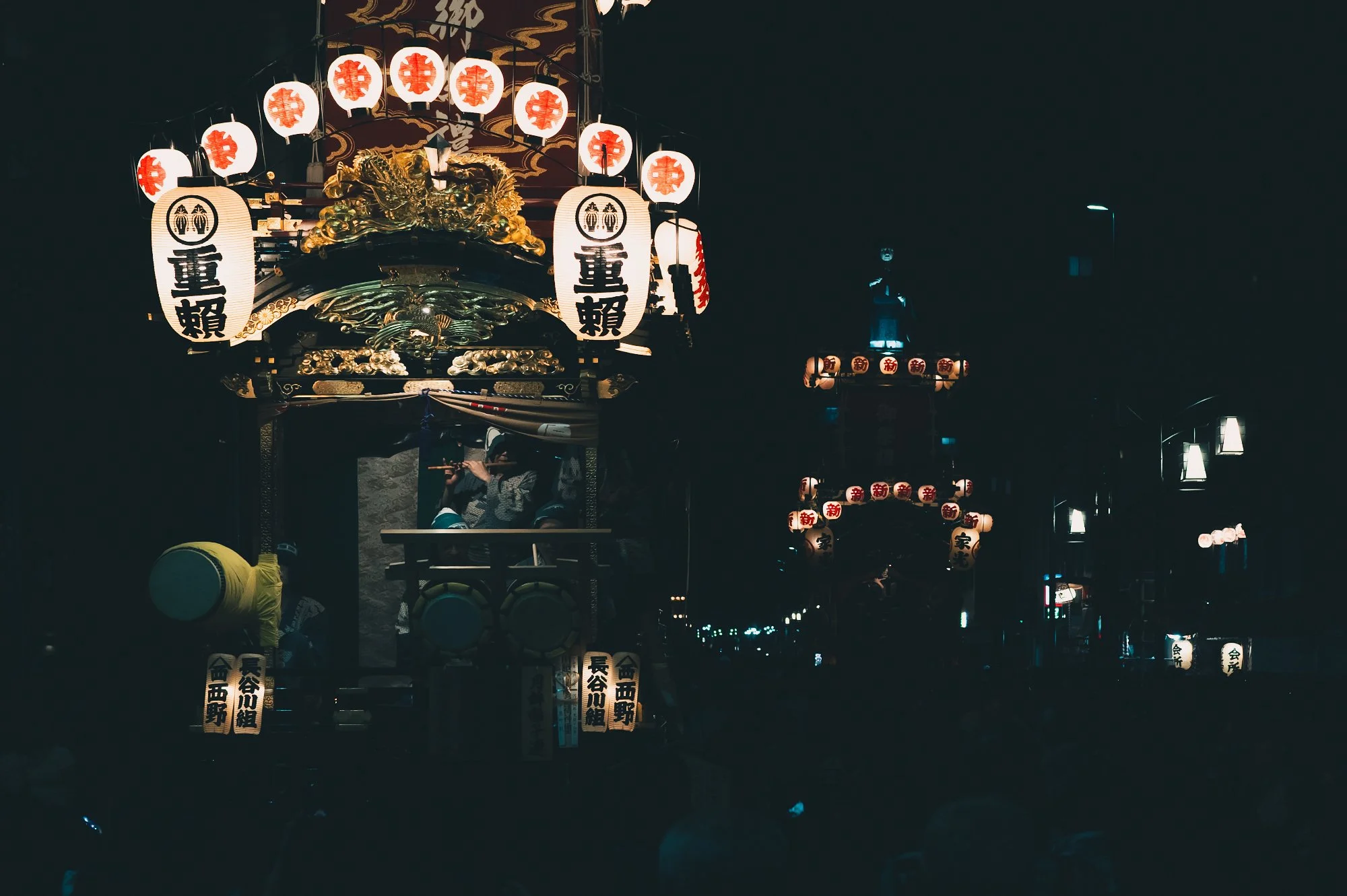 Print AD-0036. Illuminated festival floats receding into the night.