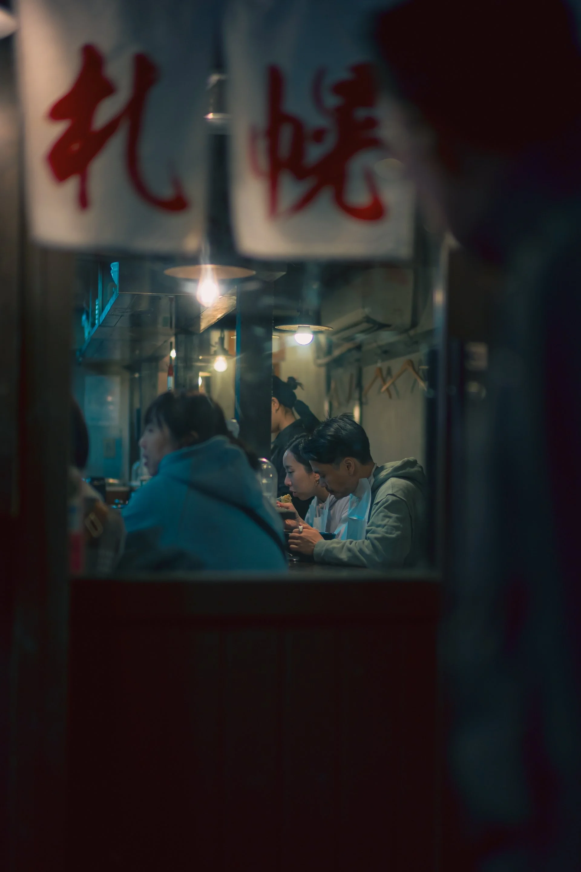 Print AD-0007. Diners glimpsed through a narrow street opening.