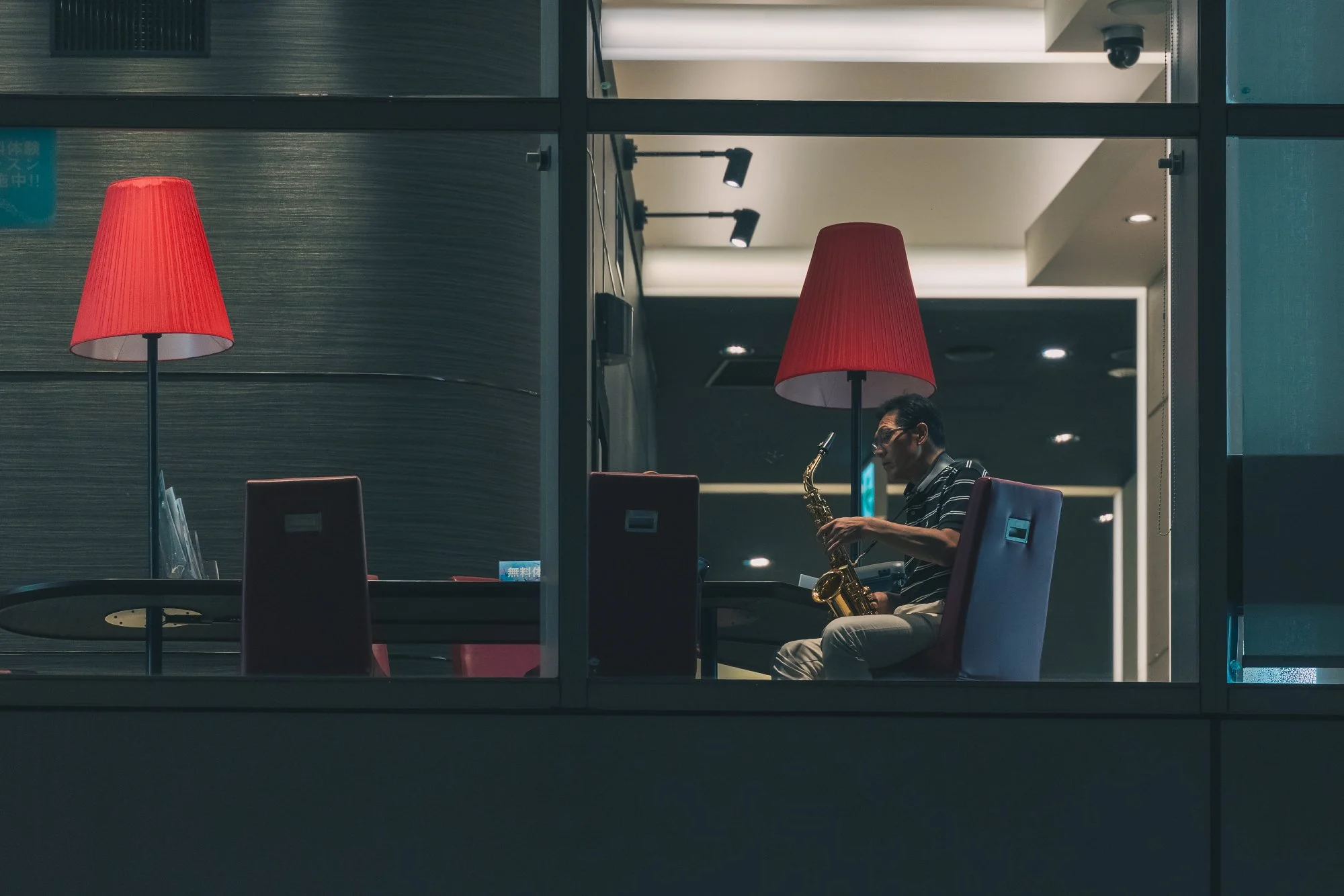 Print AD-0001. Red lamps and a figure seen through a window.