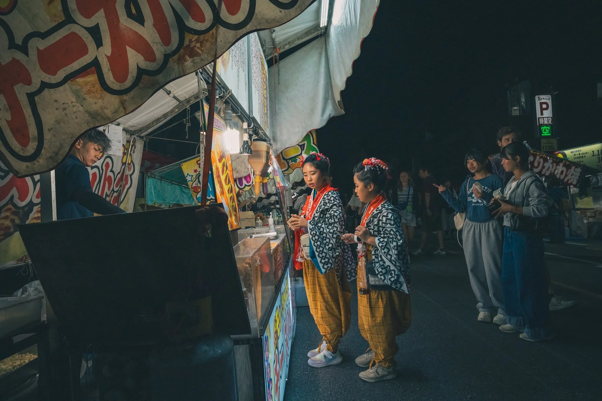 Print AD-0032. Children at a food stall after dark.