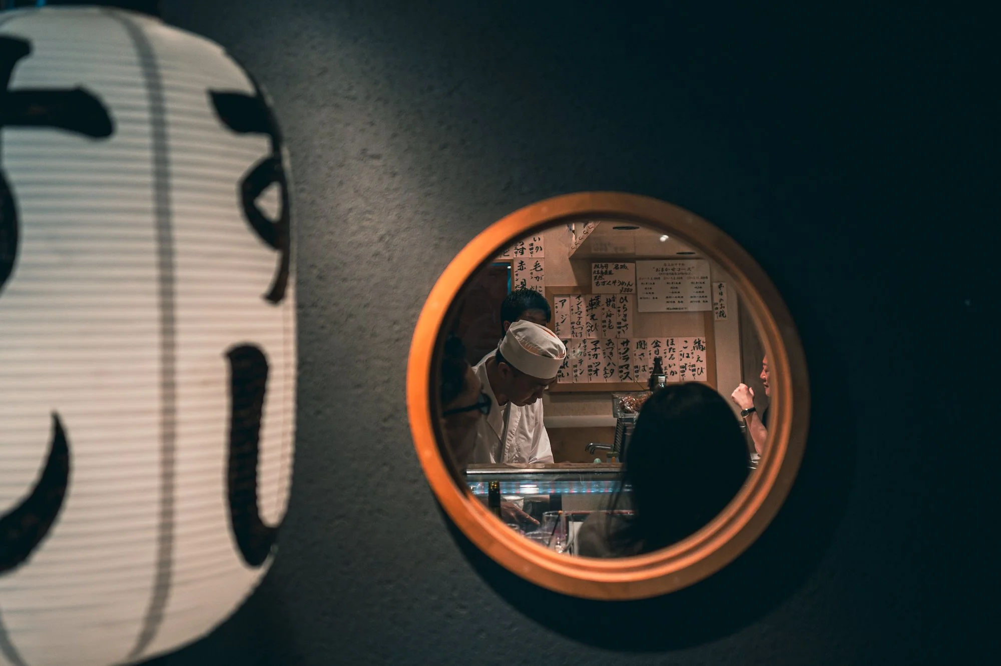 Print AD-0009. A chef and working interior seen through a circular opening.