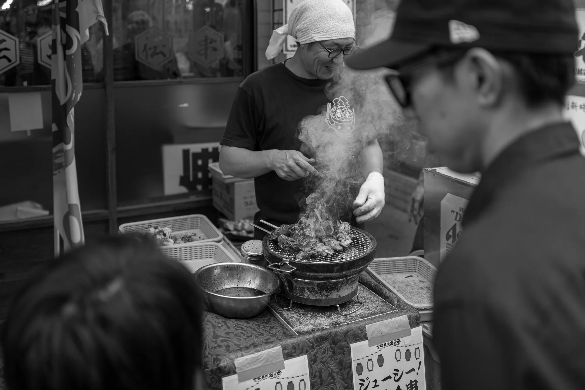 Print AD-0045. A cook tending a smoky grill as people gather nearby.