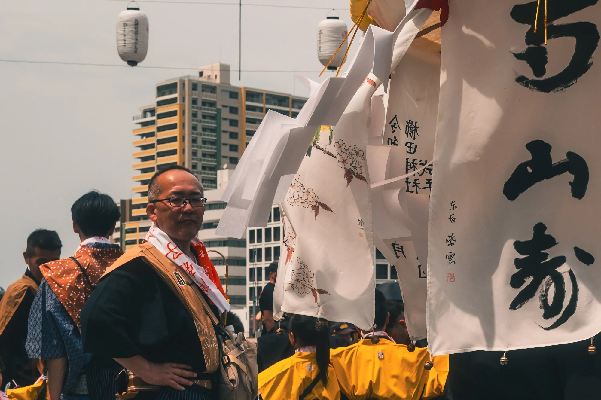Print AD-0026. A participant standing among hanging festival banners.